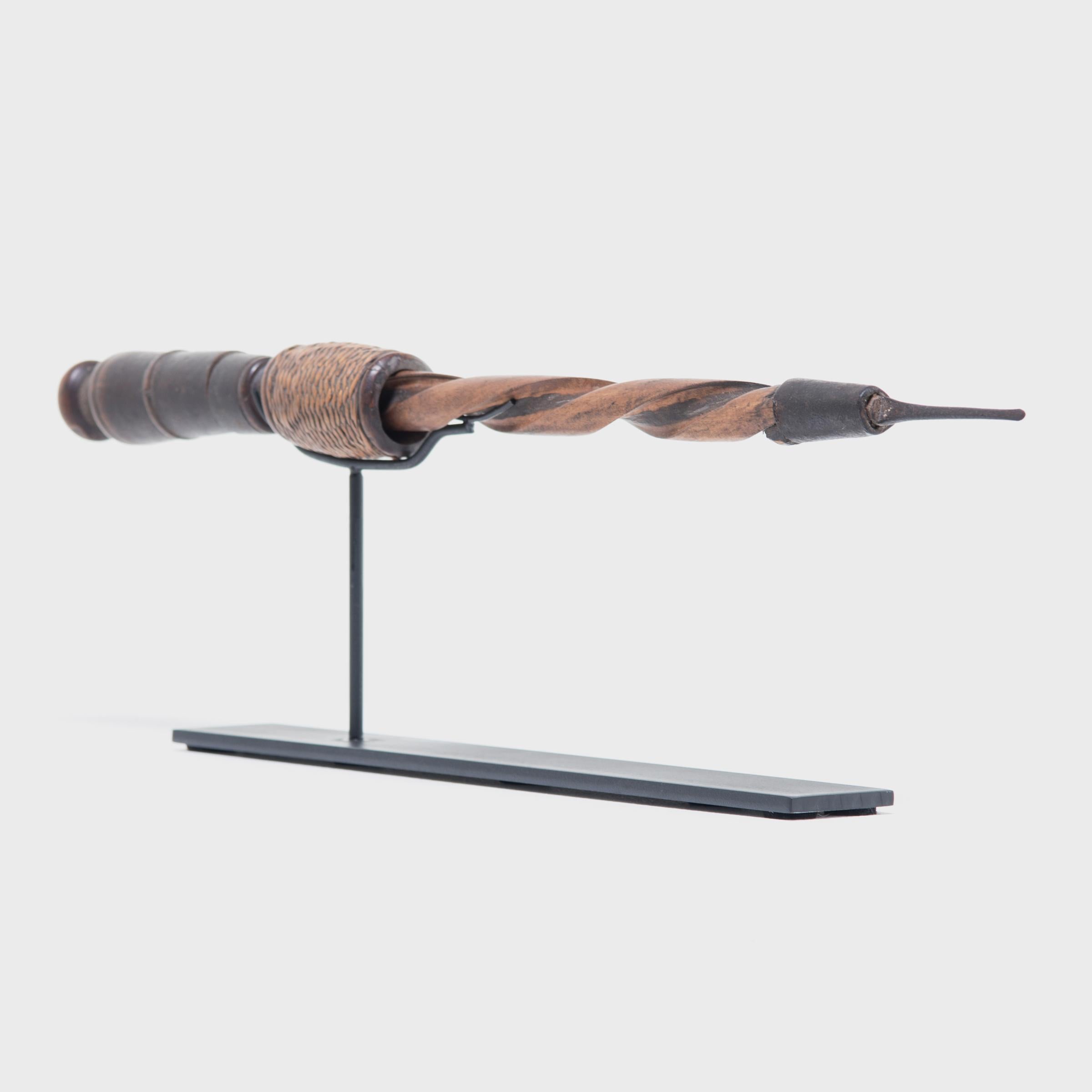 Long ago, an Indonesian artisan living on Lombok, an island well known for its weaving, made his living using this handsome handcrafted drill. The ferrule tip is copper, the tapered handle iron and the shaft carved out of wood with a woven stop. Now