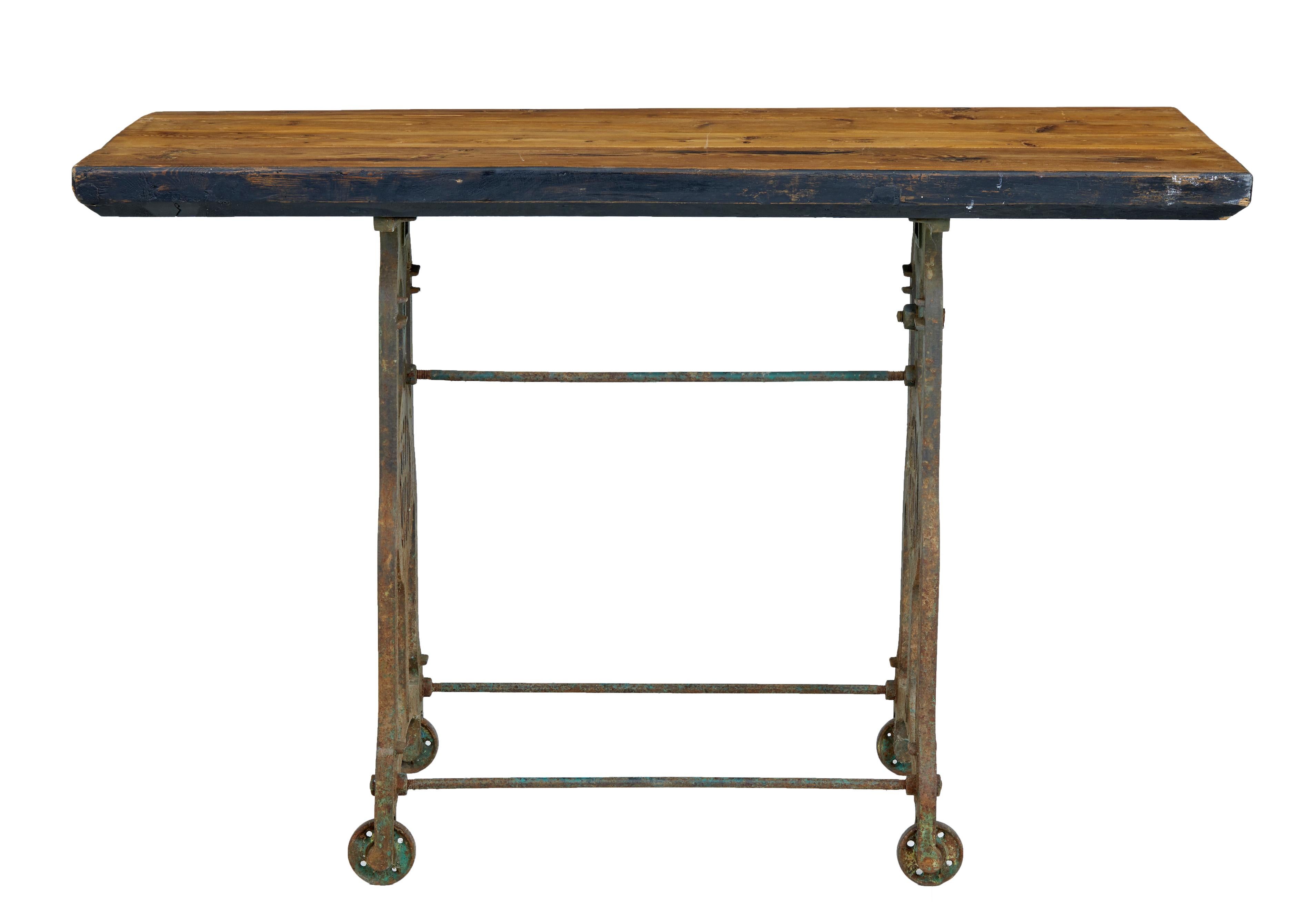 Cast iron base with thick pine top, circa 1900.

Decorative cast iron base which was formerly a sowing table base, with original green and yellow paint, intials of nhb on either end. Complete with fixed wheels. Presented with a thick 19th century