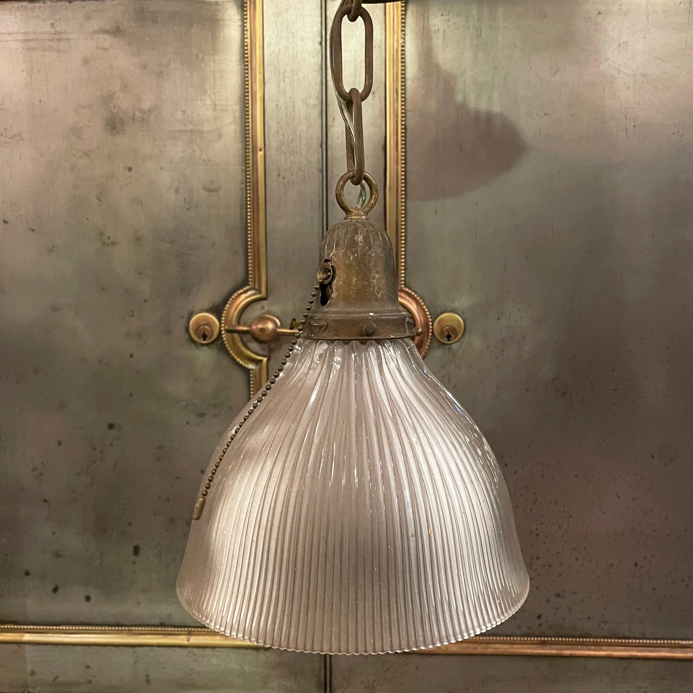 Early 20th century, industrial pendant light features a cut glass, dome shade with patinated brass pull chain fitter, chain link and canopy. The pendant hangs at an overall height of 36 inches and the canopy measures 5 inches diameter.