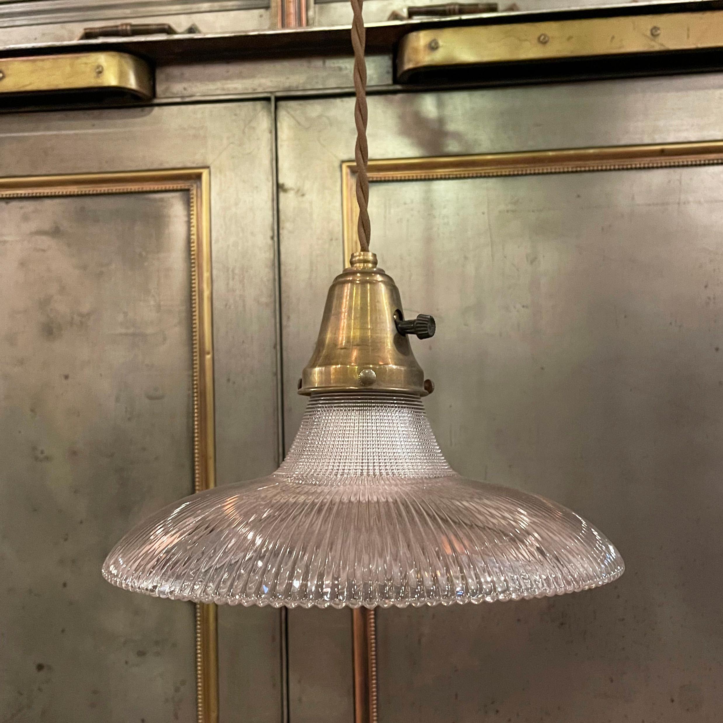Early 20th century, industrial pendant light with a curved disc, prismatic Holophane glass shade and a brass paddle switch fitter is newly wired with 48 inches of brown braided cloth cord.