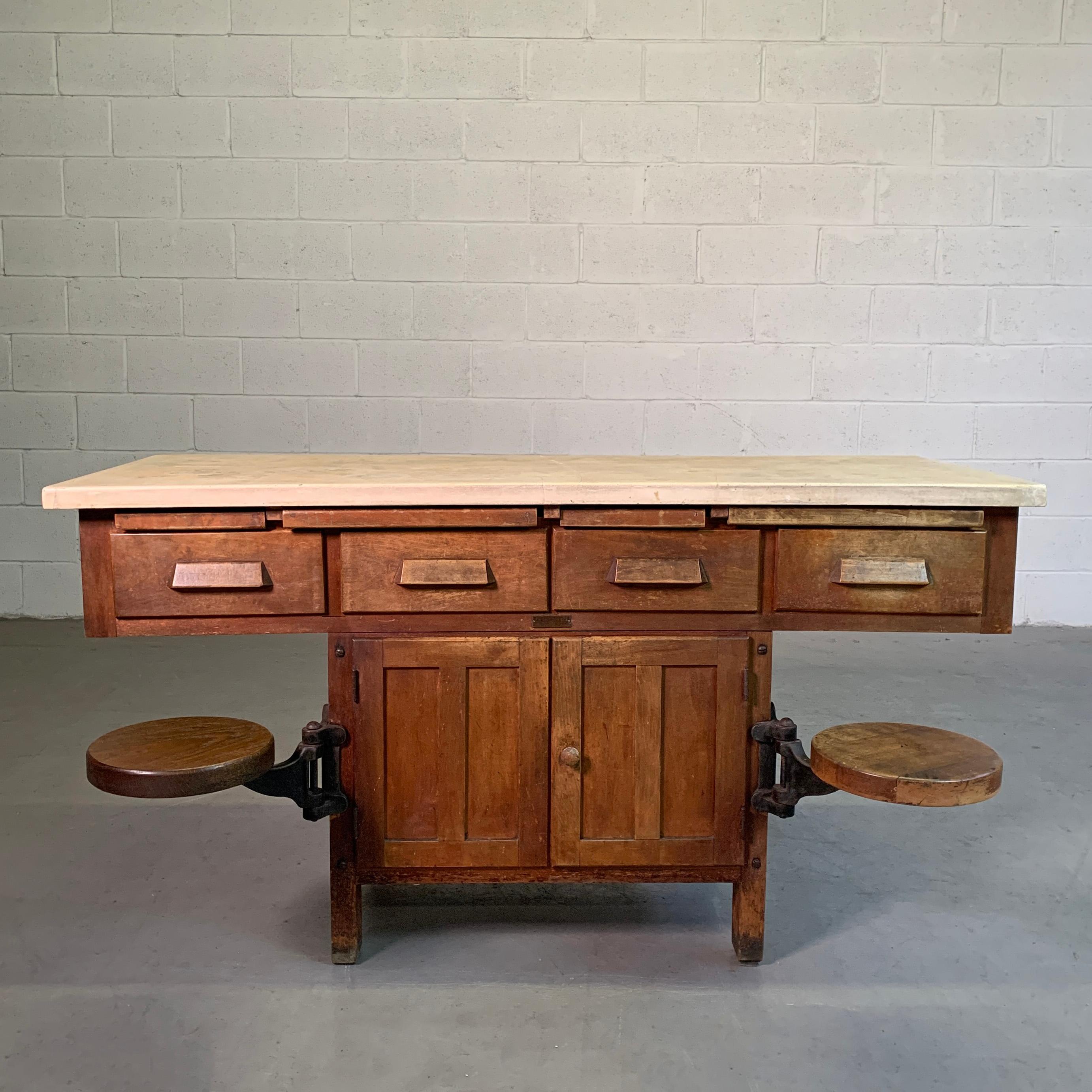 Early 20th century, Industrial, chemistry, laboratory workbench with concrete top, maple base and cast iron hardware features 2 swing-out seats, cabinet space, drawers and pull-out ledges. The seats are 10 inches diameter x 17.5 inches height with