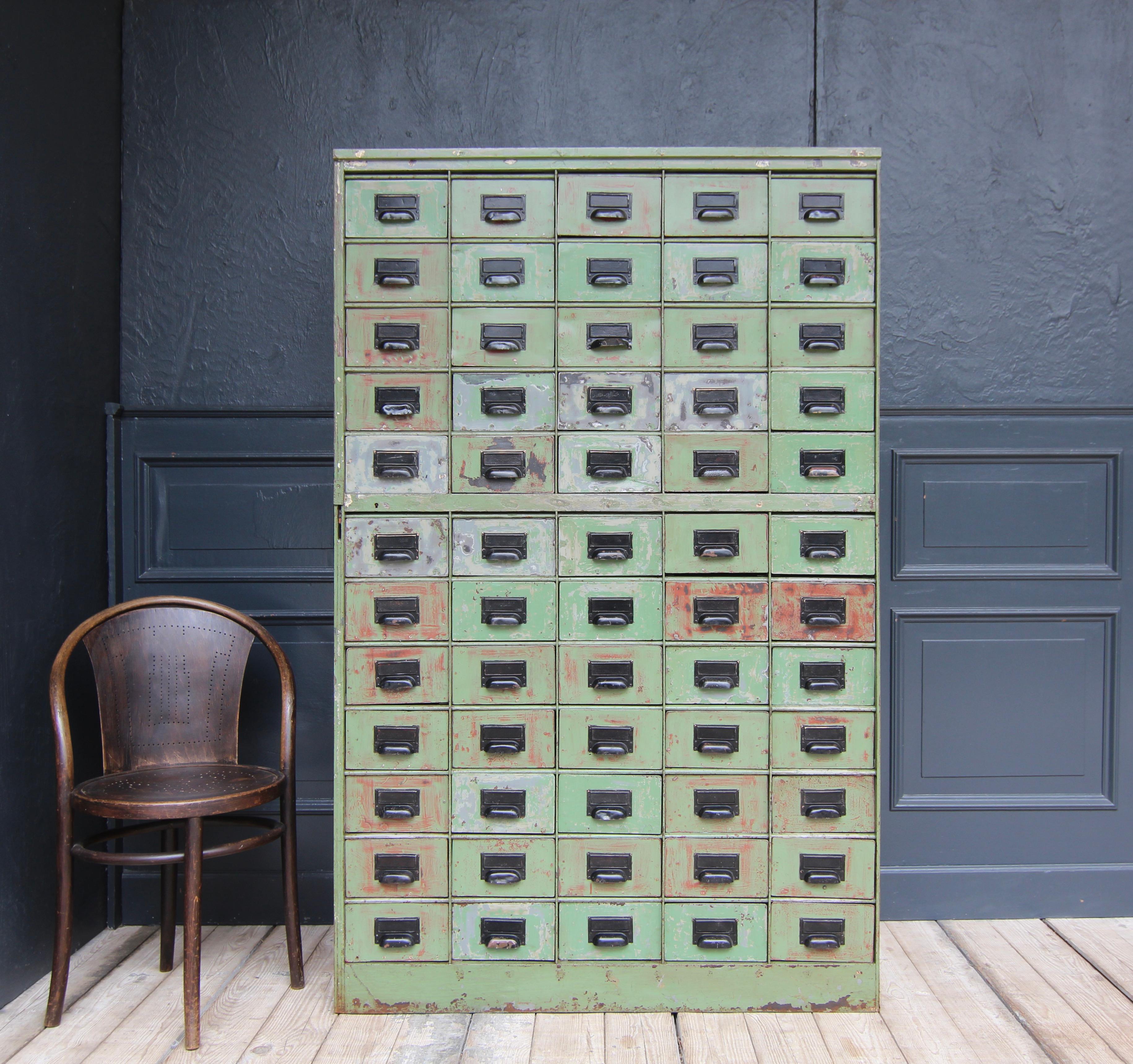 Industrieller Metall-Schubladenschrank aus dem frühen 20. Jahrhundert mit schöner Patina. Hochwertiges, robustes Design mit 60 Schubladen, jede mit einem genieteten schwarzen Griff mit Label-Halter auf der Vorderseite. 

Abmessungen
Höhe: 175,5 cm /