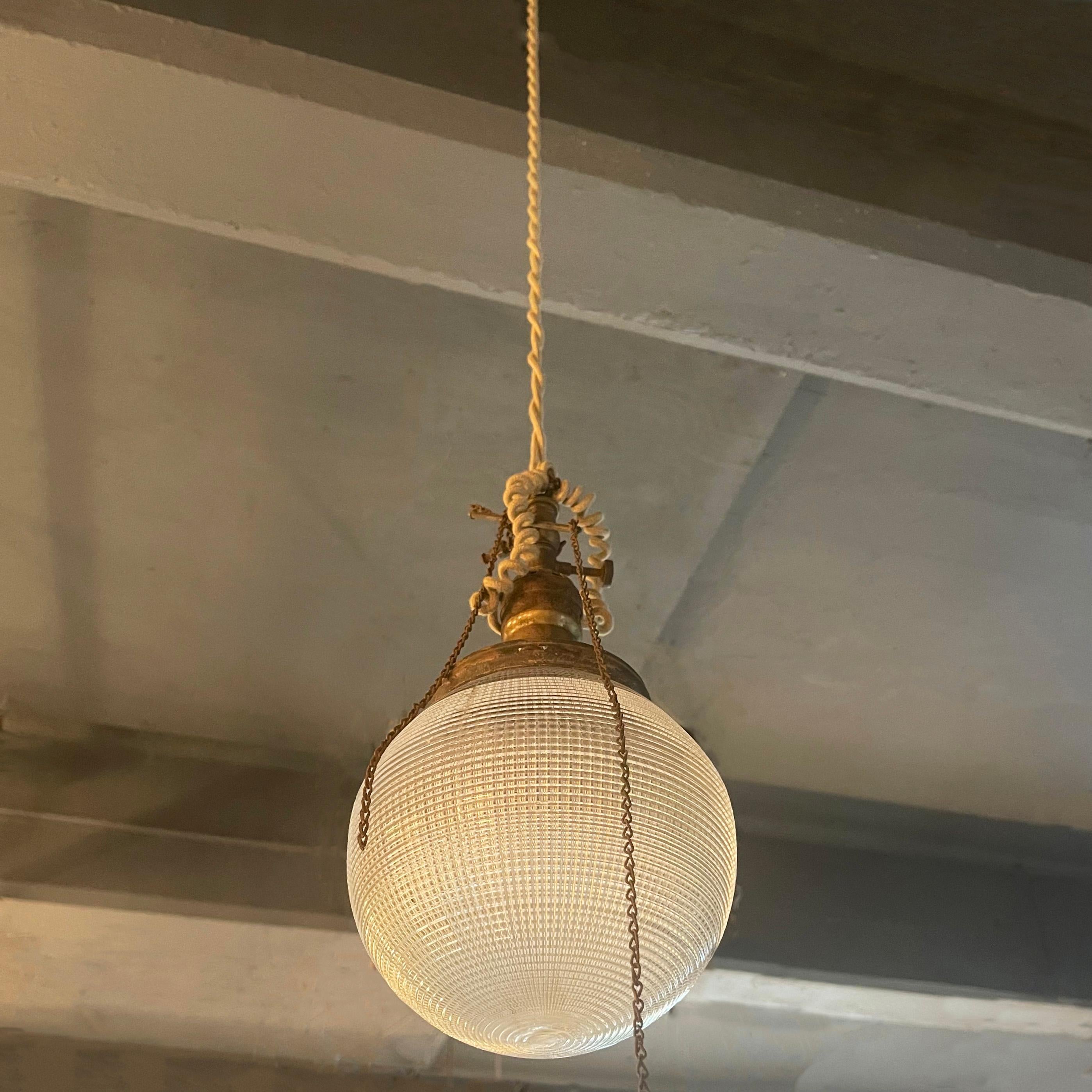 This industrial prismatic Holophane globe pendant light comes from an era of superior craftsmanship offering a unique blend of enduring quality and classic elegance that seamlessly fits both modern and period interiors. The defining feature of the