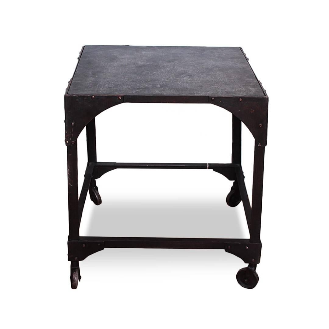 A vintage industrial low square table with rivet detailing and casters, USA, circa 1930.