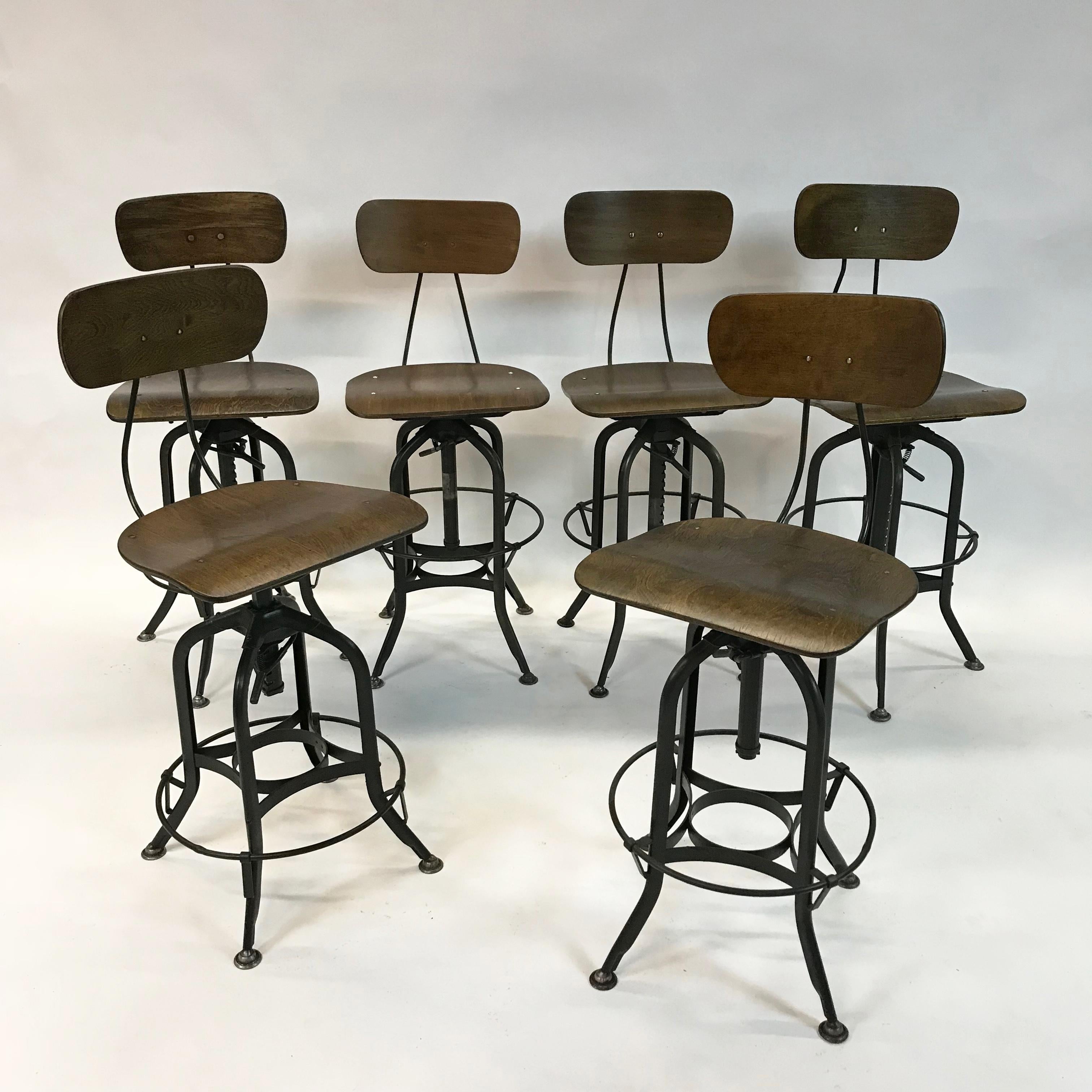 Early 20th century, Industrial stools by Toledo Metal Furniture Co. feature newly finished, bent ply, potato chip seats and backs with painted steel, star bases with round foot rests. Seat heights on five of the stools are adjustable from 25-32