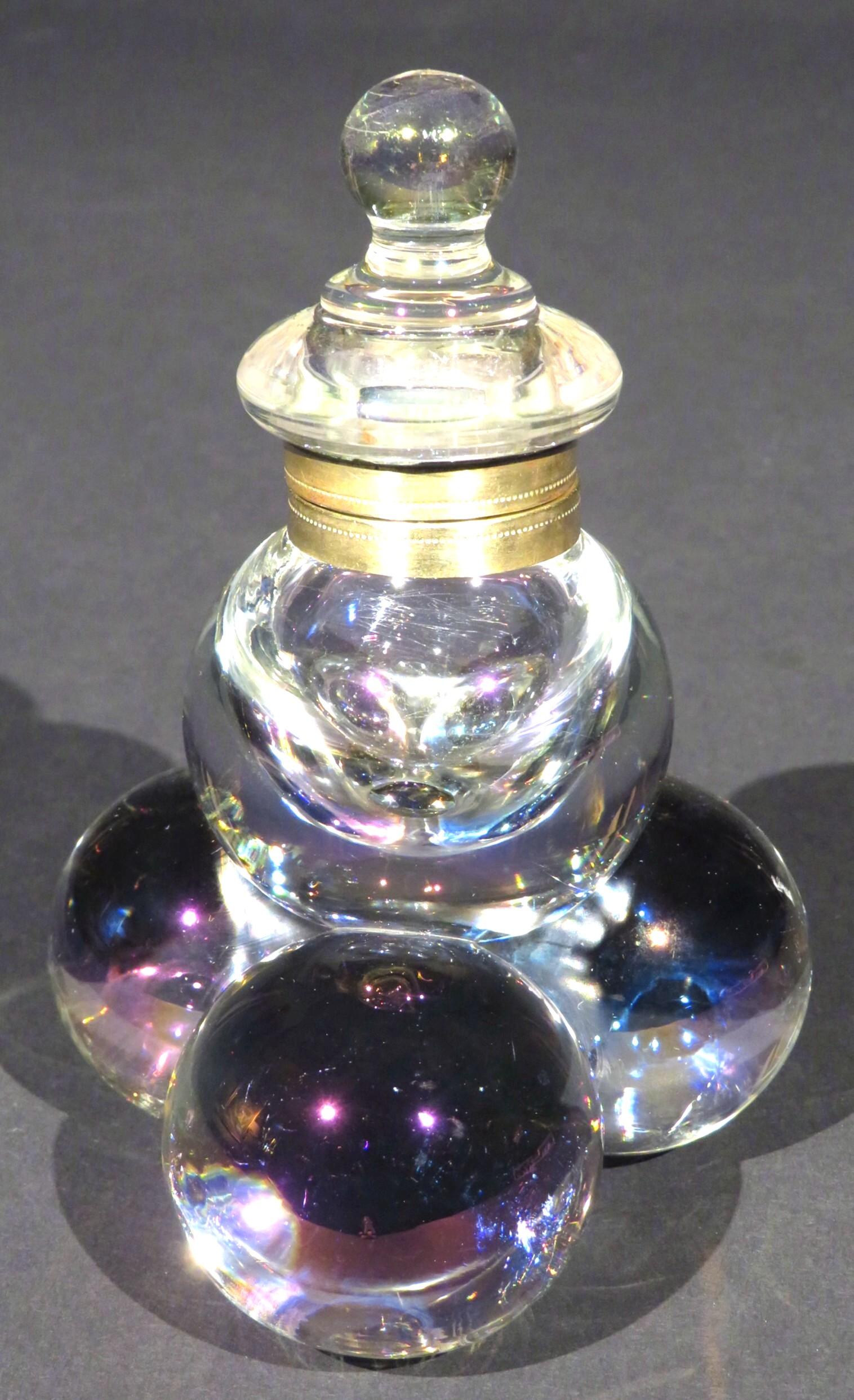 The hinged top fitted with brass mounts to a spherical well, raised atop a trio of smaller spherical supports all having a subtle iridescent quality.

 