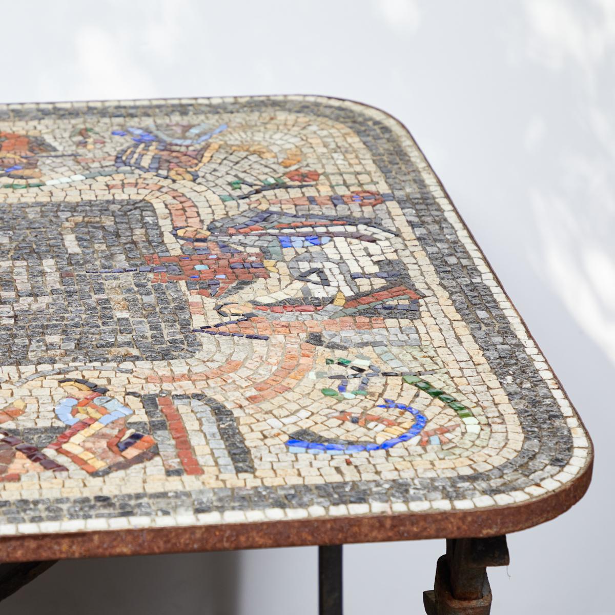 Mosaic topped iron table from turn-of-the-century England. The beautiful mosaic surface contains a number of figurative representations arranged in a ring around a central panel depicting water. This wonderful example of artistry and craftsmanship