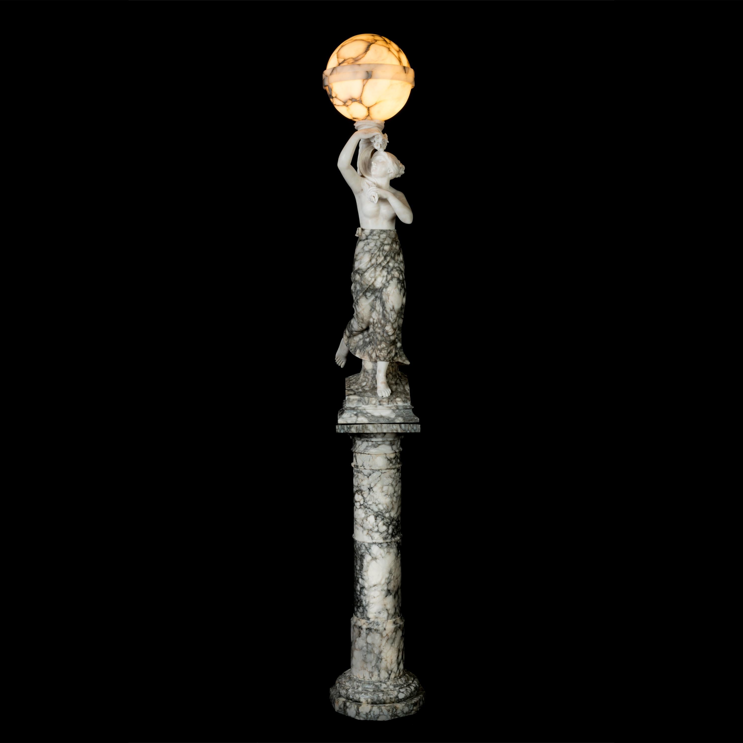 Una lampada italiana in alabastro figurato

Scolpita da due tipi di alabastro a contrasto, sostenuta da un piedistallo colonnare, la figura femminile è drappeggiata con una gonna, con un globo galleggiante sopra la testa, collegato