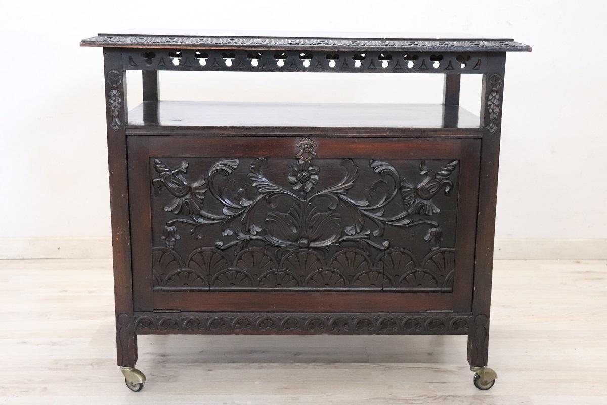 We are excited to present this unique early 20th-century bar trolley, crafted in Italy during the elegant Art Nouveau period. This striking piece is characterized by its refined carved floral decorations on the two doors, which add a touch of