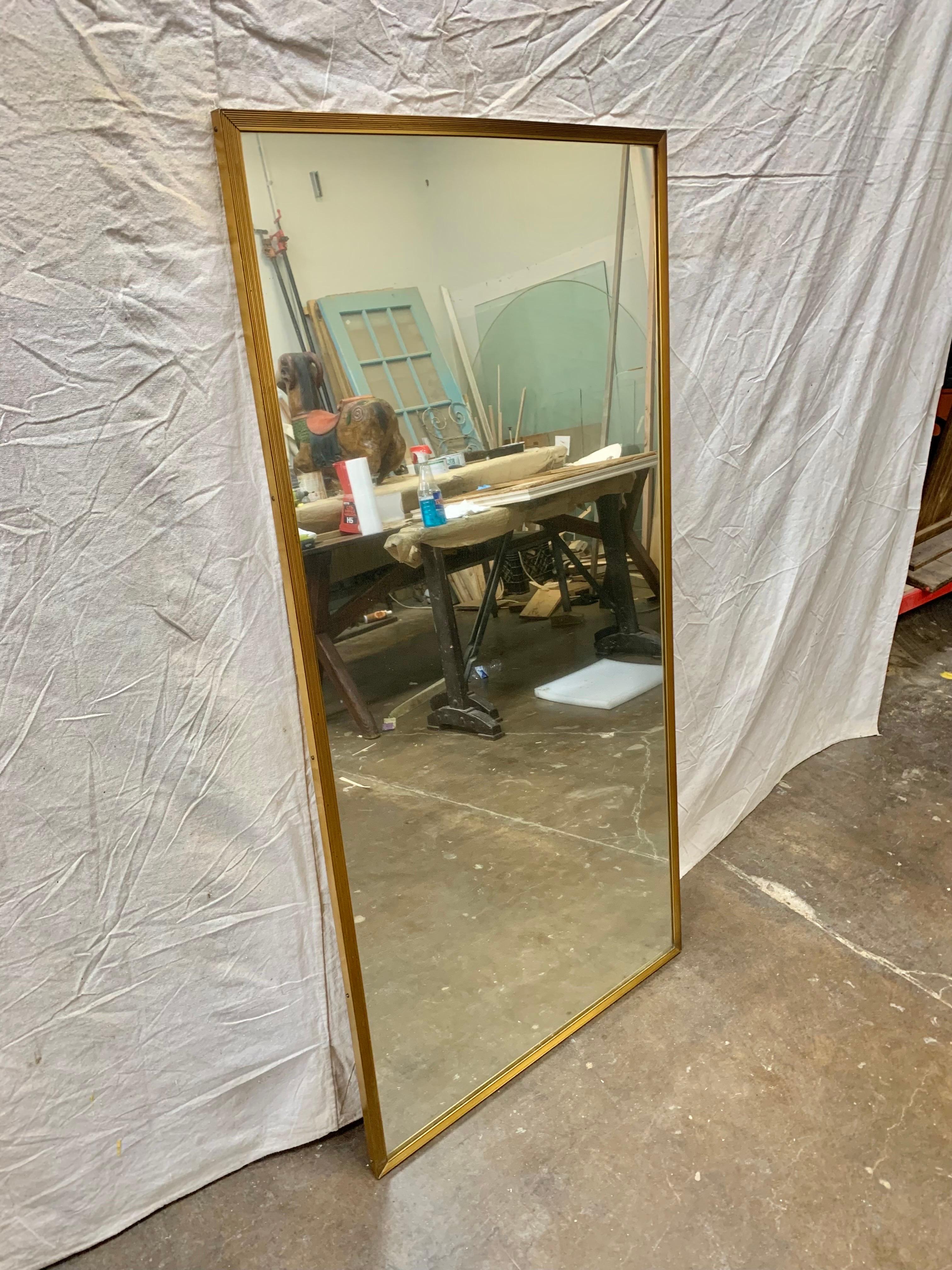 Trouvé en Italie, ce miroir mural italien du début du 20e siècle présente un magnifique cadre cannelé et étroit en laiton. De forme rectangulaire, le miroir présente un style minimaliste et moderne élégant et distinctif. Le cadre et le miroir en