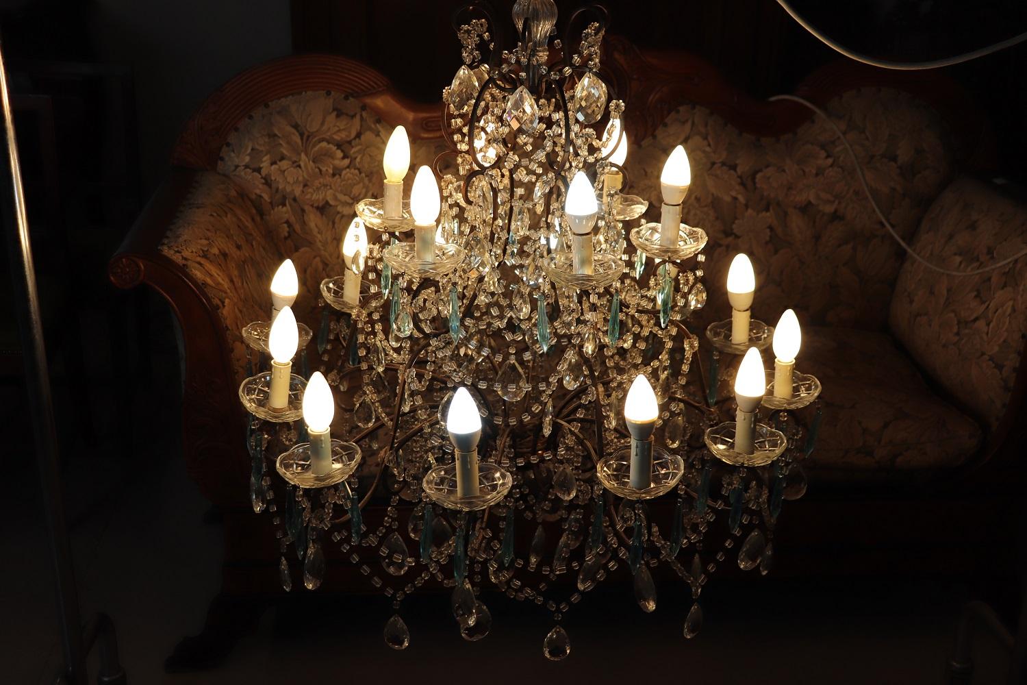 Beautiful and refined Italian 1930s chandelier with 18 bulbs. The lights are arranged on two floors. In patinated bronze completely covered drops of rare colored blue crystal and transparent crystal. The crystals exudes the typical brightness; the