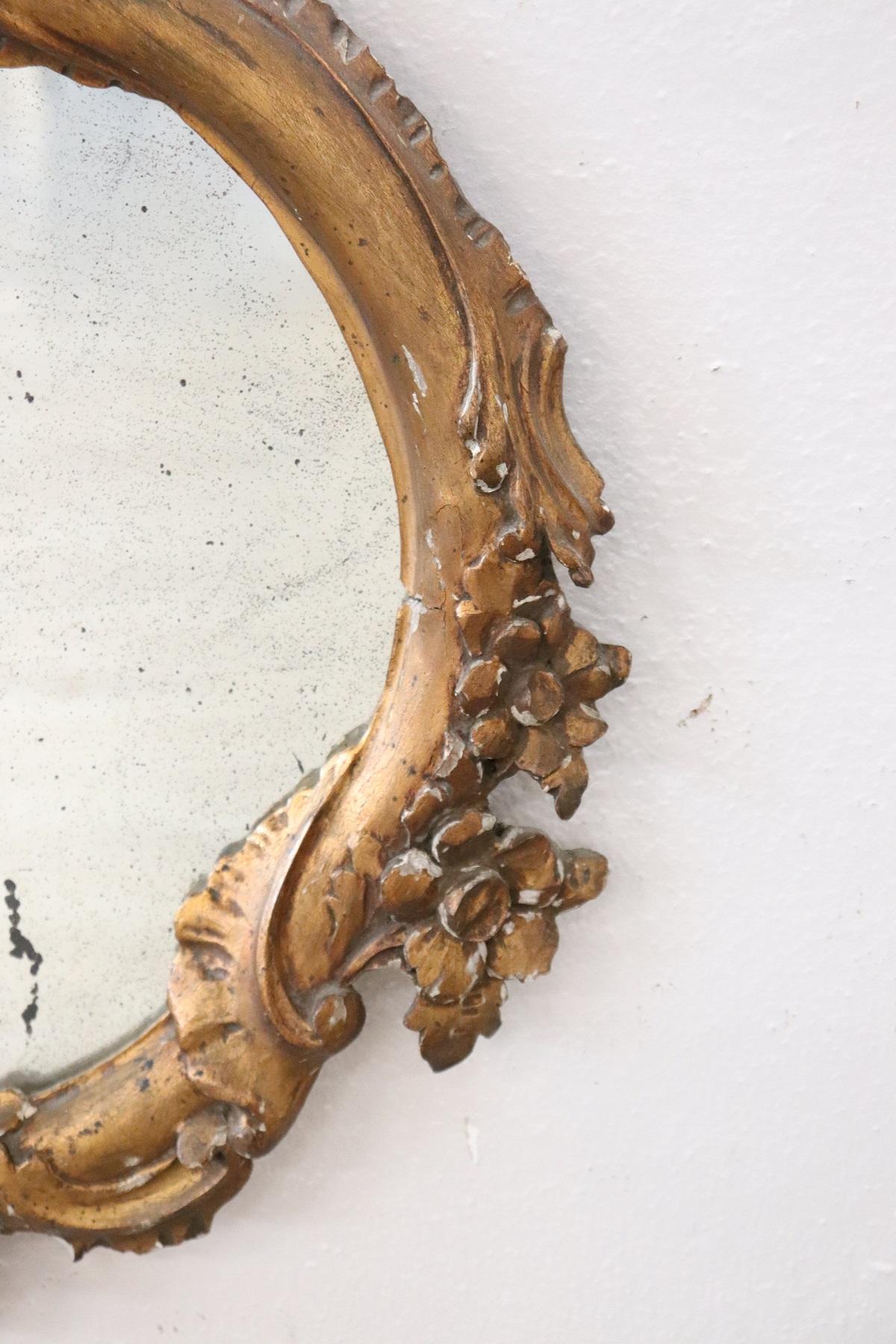 Beautiful elegant wall mirror in 1930s wood hand carved with finely and richly swirls, curls. Refinement decorated in gold. Antique mercury mirror.