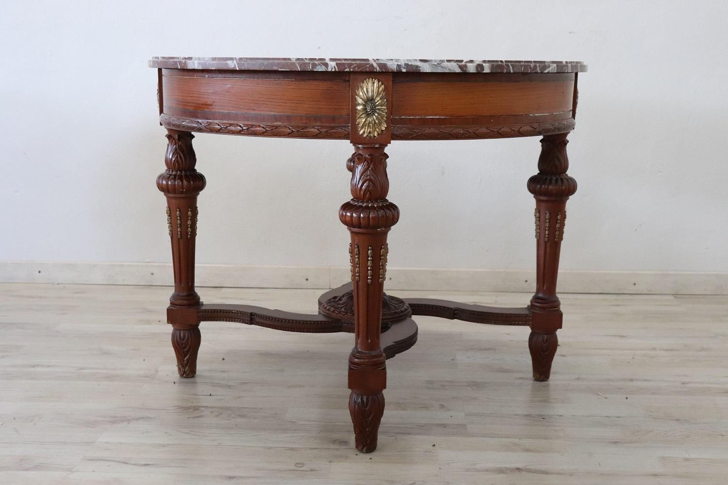 Beautiful important round center table 1930s in carved walnut. The top is supported by four turned and carved legs. The top is in fine red marble. Perfect conditions. Ideal table to embellish the center of a room.