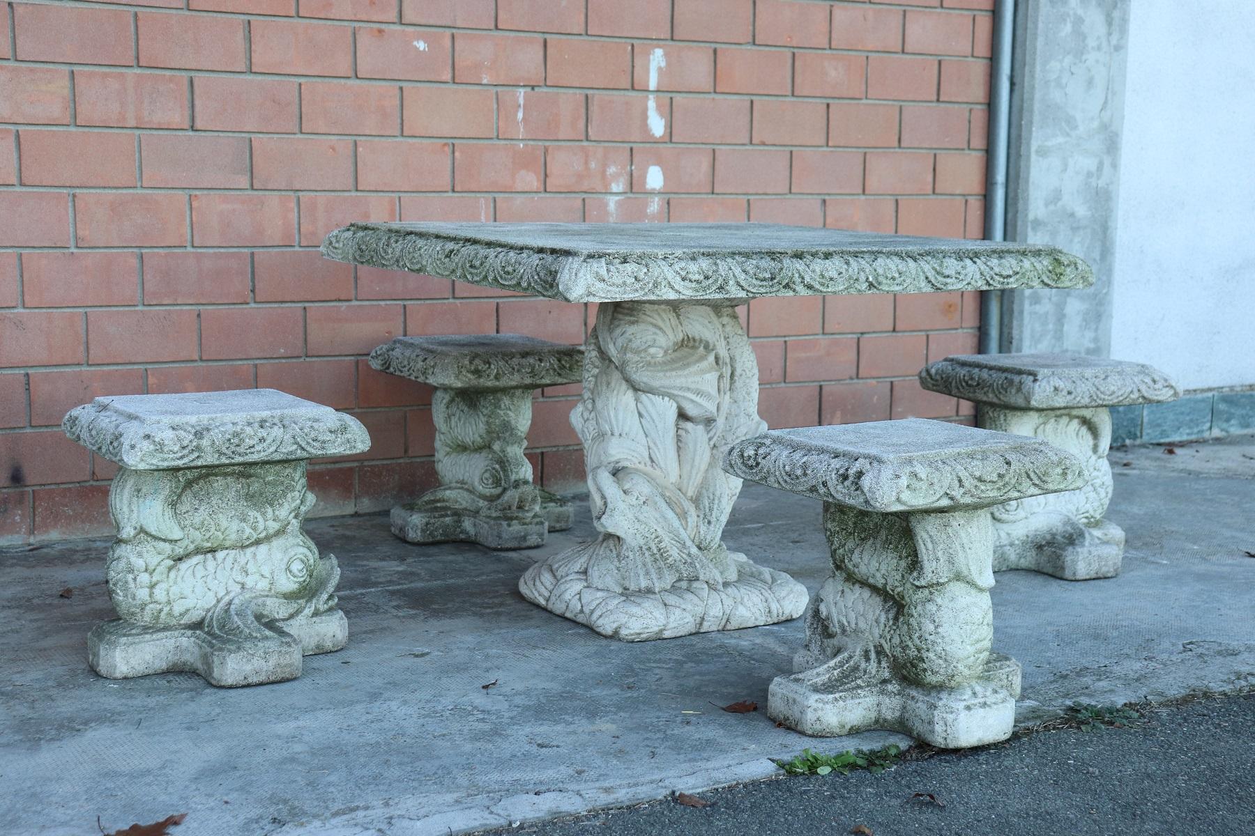 Beautiful refined garden set in Charlex style, circa 1920s main material stone mixed with gravel and cement. Beautiful square table with four stools. Gorgeous carved decoration with large tritons supporting the table top and the seats of the stools.
