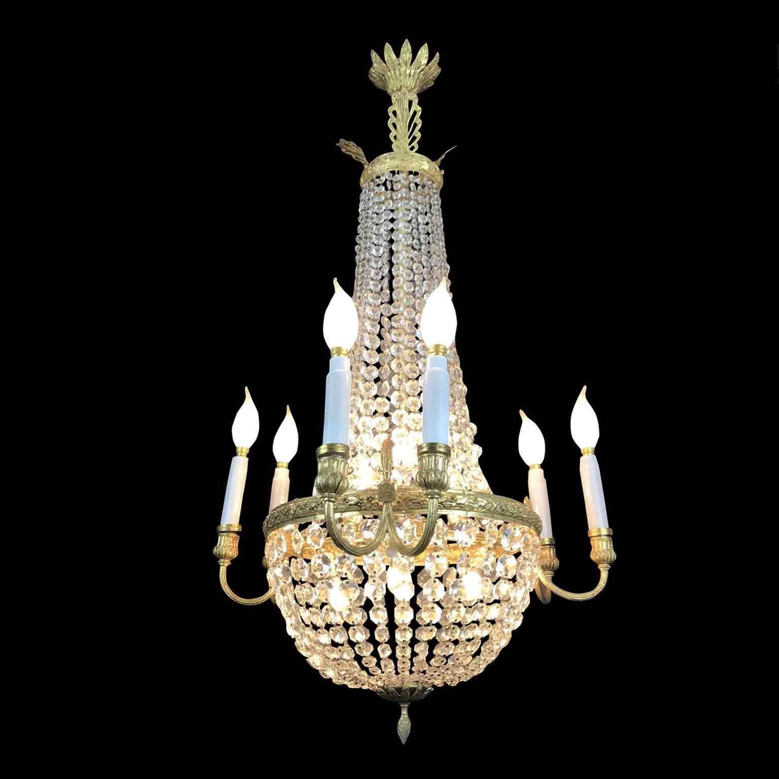 A charming twelve-light Empire style Italian crystal chandelier, a gilded cast bronze chandelier realized in Italy in the early 20th century, richly decorated with waterfall crystal festoons, an ormolu circular structure decorated by cast and