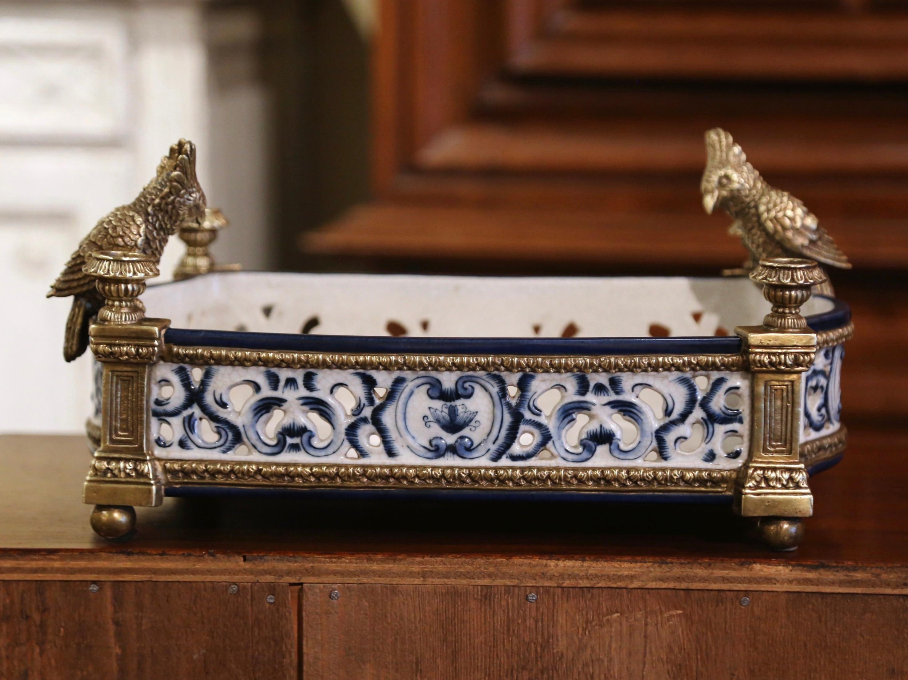 Decorate a dining room table or dress a console with this elegant antique centerpiece. Crafted in Italy circa 1920, the colorful dish stands on bronze round feet over side columns. Rectangular in shape with bombe sides, it features a blue and white