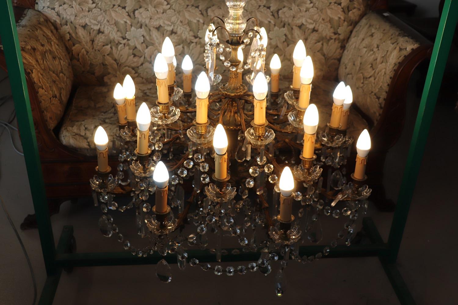 Beautiful and refined Italian 1930s chandelier with 24 light bulbs. The lights are arranged on different floors. In gilded chiseled bronze completely covered drops in transparent crystal. The crystals exudes the typical brightness; the drops are