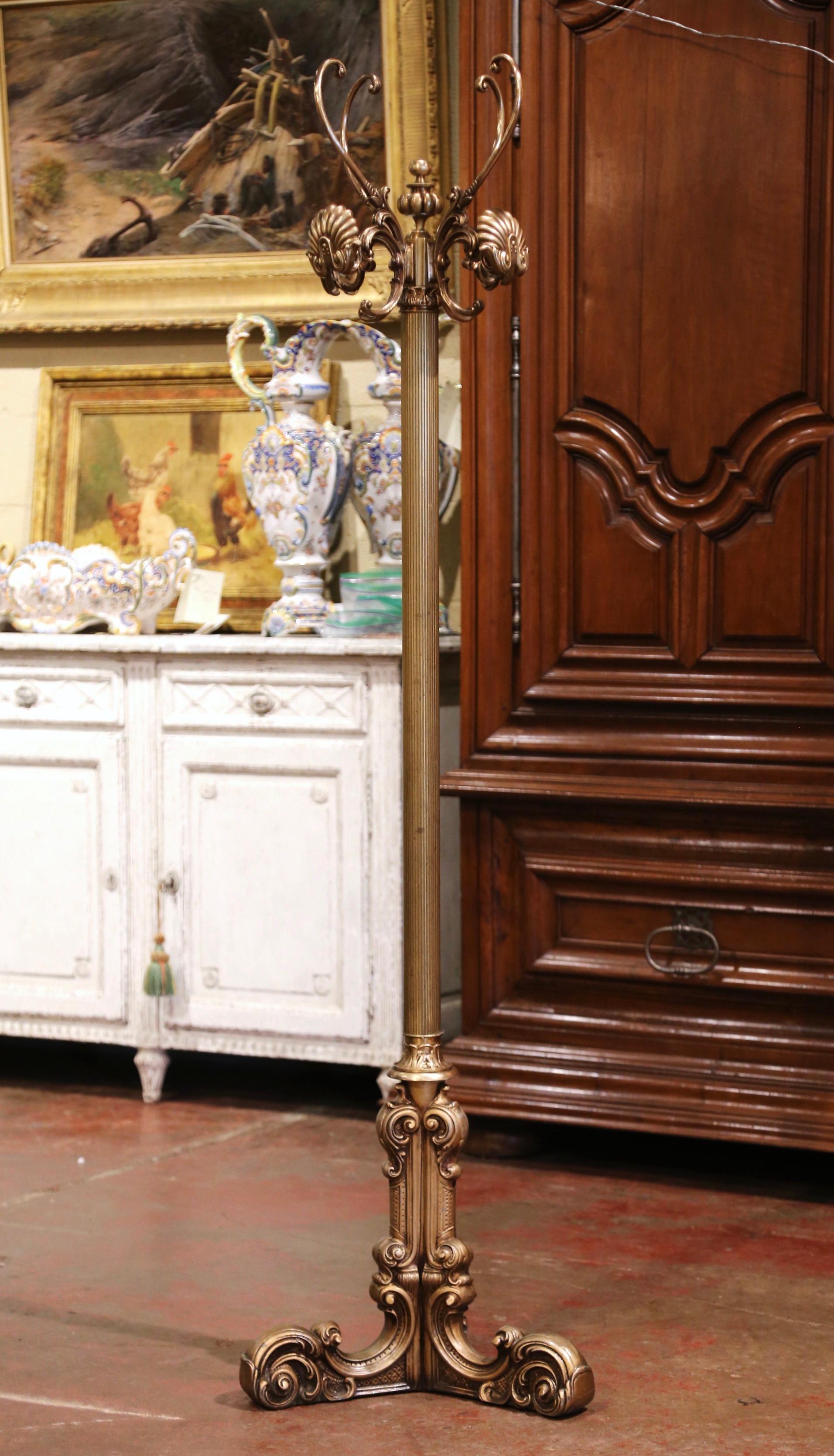This antique brass hall tree was crafted in Italy circa 1920. Standing on a intricate base with three scrolled legs ending with leaf decor feet, the rack features a tall fluted central stem. The top dressed with a central finial, features a swivel