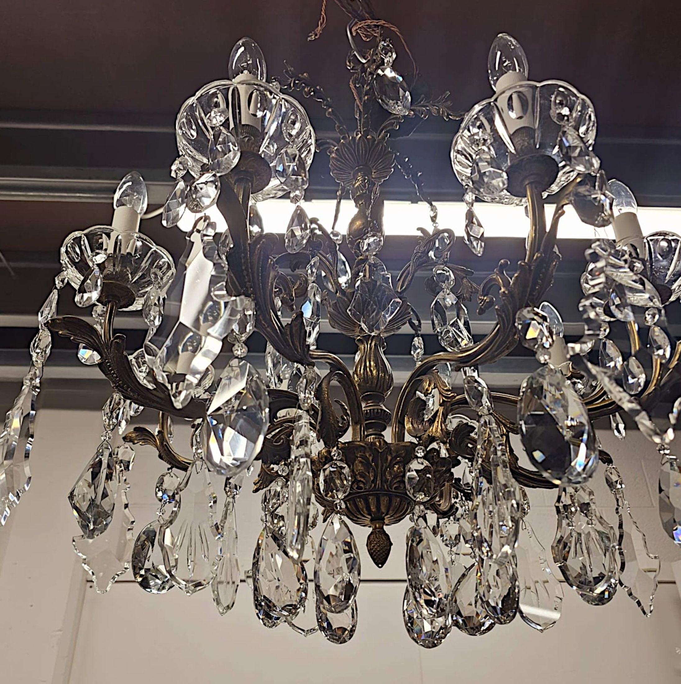 Stupendo lampadario a otto bracci in bronzo dorato e cristallo dei primi del Novecento italiano, di qualità eccezionale.  Questo pezzo in bronzo dorato finemente fuso è caratterizzato da una colonna centrale tornita e scanalata ornata con motivi