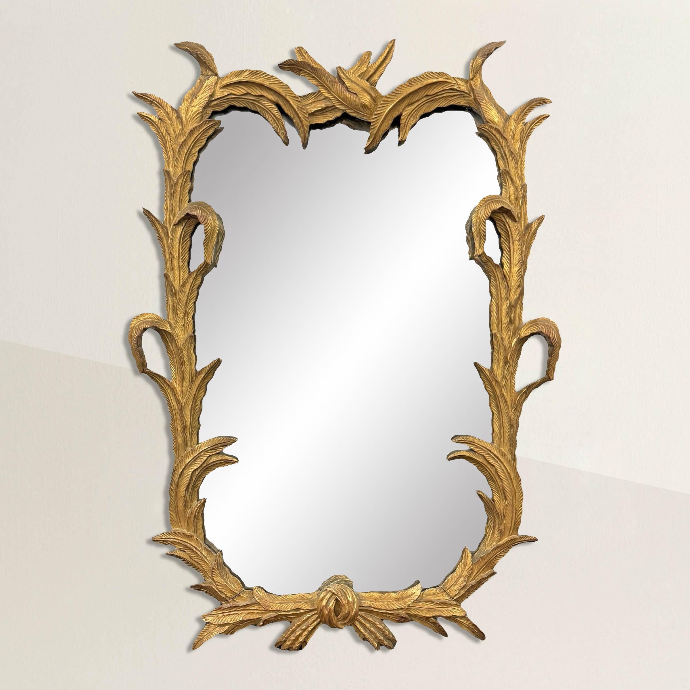 This early 20th-century Italian carved and gilt wood framed mirror is a masterpiece of artisanal craftsmanship, boasting an intricate and enchanting design. The frame is a symphony of detail, with dozens of stylized feathers meticulously carved and