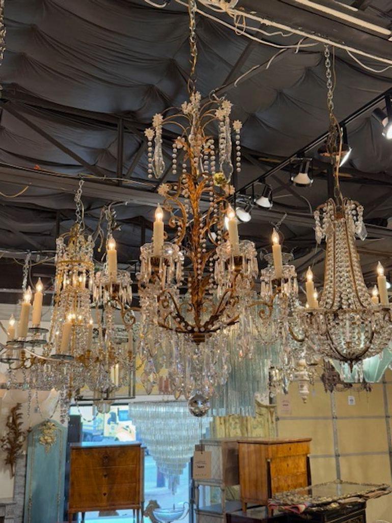 Le produit est un lustre italien antique du 20e siècle en toile dorée et cristal. Le lustre dégage vraisemblablement une esthétique luxueuse et élégante avec sa combinaison de toile dorée et de matériaux en cristal, ce qui en fait une pièce de