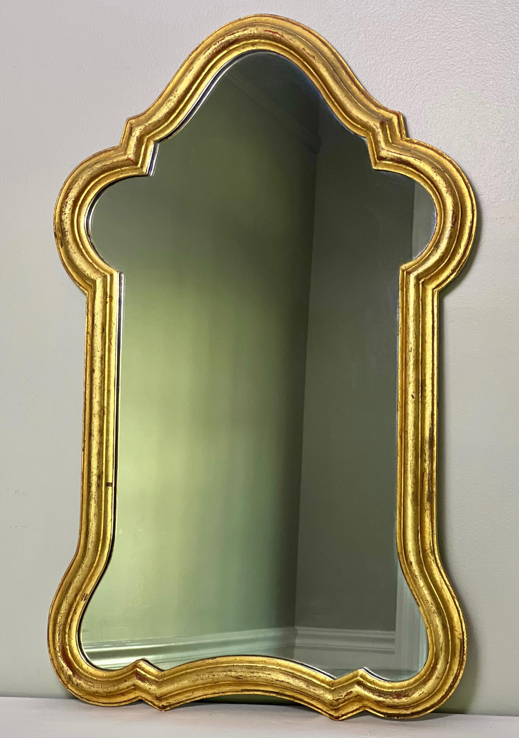 Anmutig geschwungener italienischer Bogenspiegel aus vergoldetem Holz, ca. 1930-35. Der formschöne, geschnitzte Rahmen weist eine exzellente Patina auf und hat eine klare und raffinierte Form, die die Präzision des Designs des Spiegels