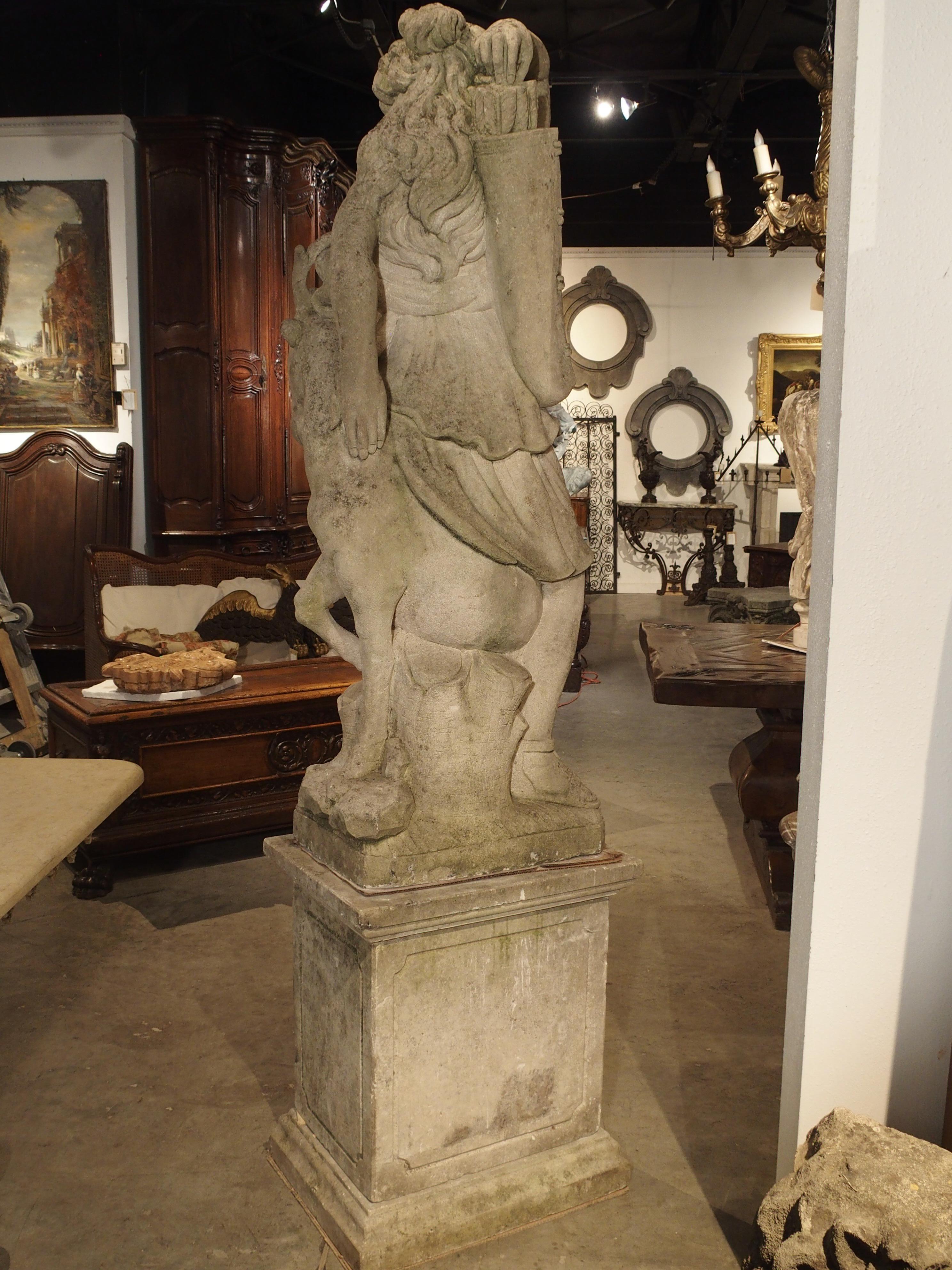 This hand carved Italian statue was made in the early 1900s using Northern Italian limestone. It represents a wonderful version of Diana the Huntress with Stag. Diana is holding the back end of a deer between her legs as she reaches for an arrow in