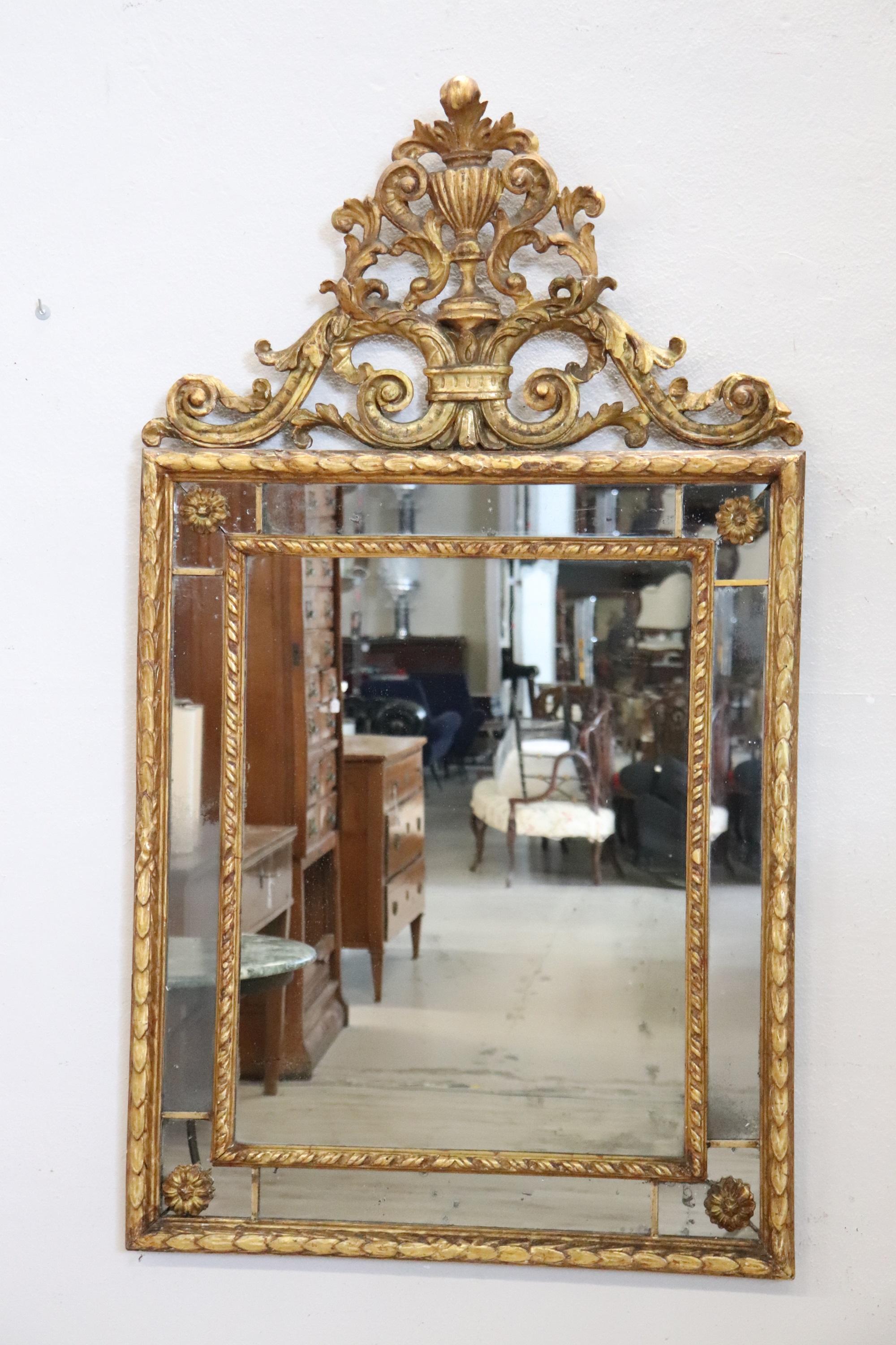 We present this elegant antique Italian mirror dating back to the early 20th century. An extremely refined mirror.

Made with a finely gilded wooden frame, its rectangular shape features a highly decorative upper section with elaborate curls and