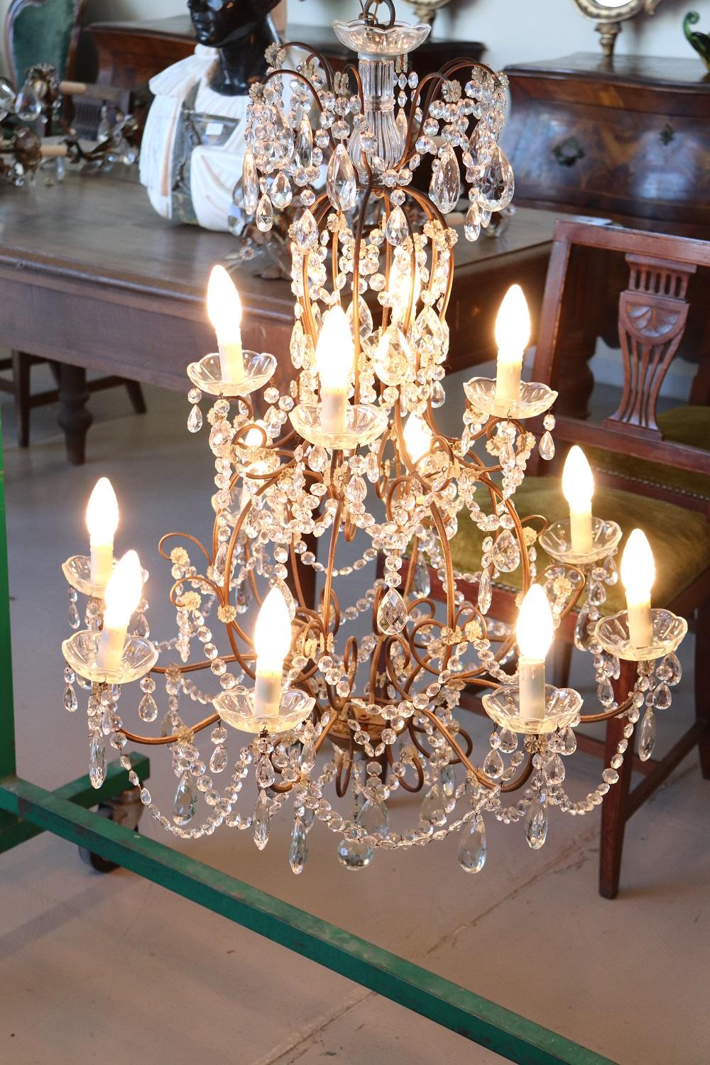Beautiful and refined Italian Louis XVI style, 1920s chandelier twelve lights arranged on two floors. In bronze and completely covered drops of crystal. The crystal exudes the typical brightness; the drops are finely worked giving an elegant light.