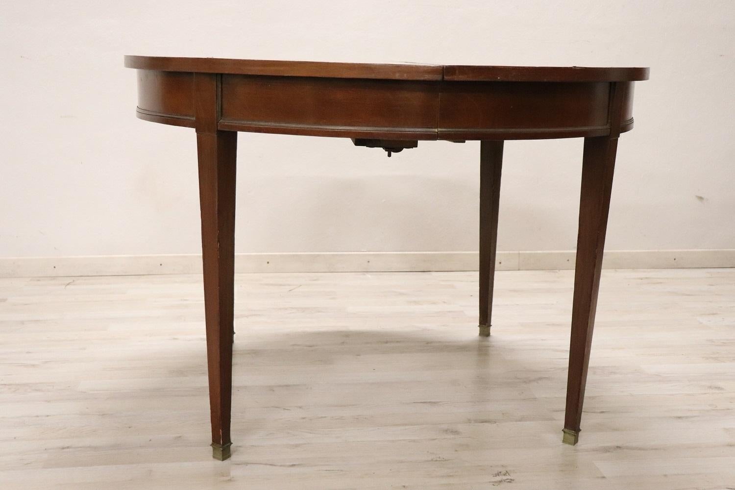 Beautiful important round dining room table, 1930s in solid walnut wood. This table is perfect for a dining room, it extends into the center becoming a large table that can accommodate many people. The four legs are elegant and slender in Louis XVI