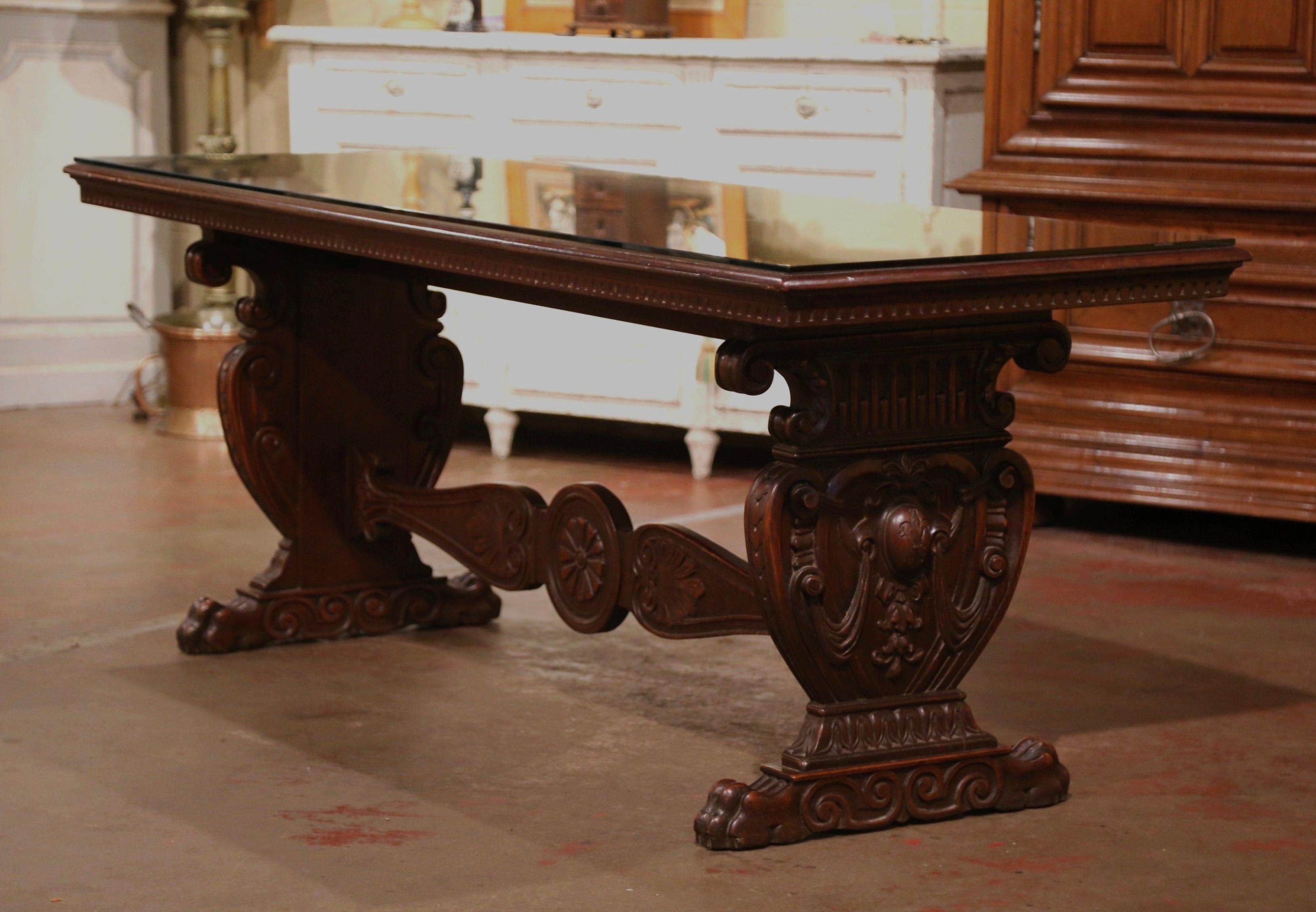 Bring the Italian elegance in your home with this important, antique Renaissance revival console table. Crafted in Italy circa 1920 and built of mahogany wood, the trestle table stands on carved pedestal legs ending with paw feet. Both scrolled legs