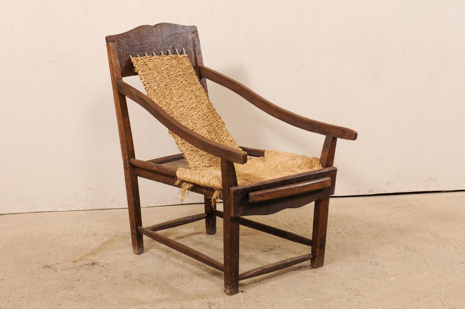 An Italian sling chair from the early 20th century. This antique lounge chair from Italy features a solid wood frame with beautiful hand-rolled rushing about the seat and back. The wood chair frame has a gently scalloped crest rail at back, which is