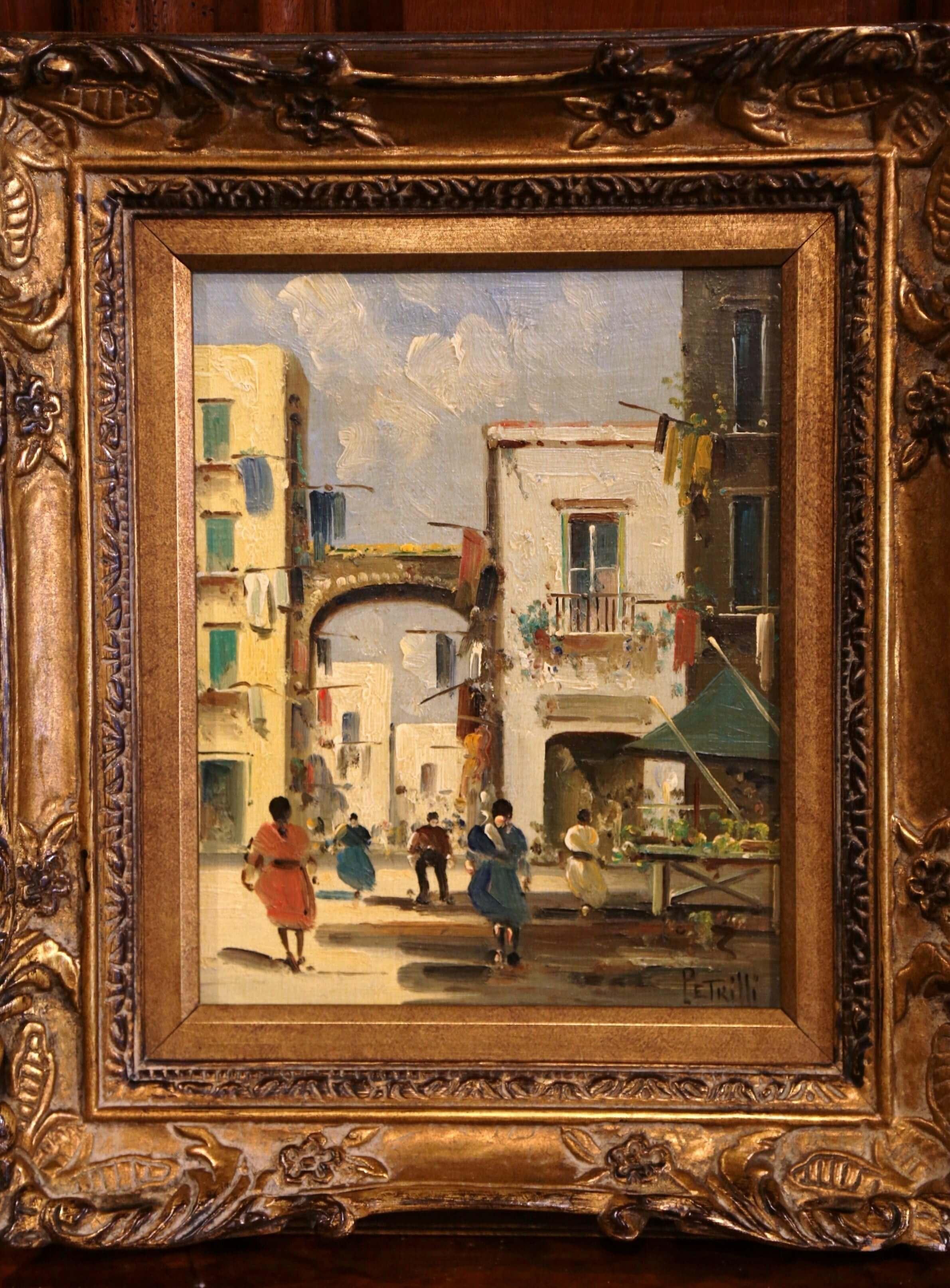 This oil on canvas painting was created in Italy, circa 1920. Set inside the original carved gilt frame, this painting depicts a European city scene bustling with people walking down the street. Buildings and anonymous figures diminish in size and
