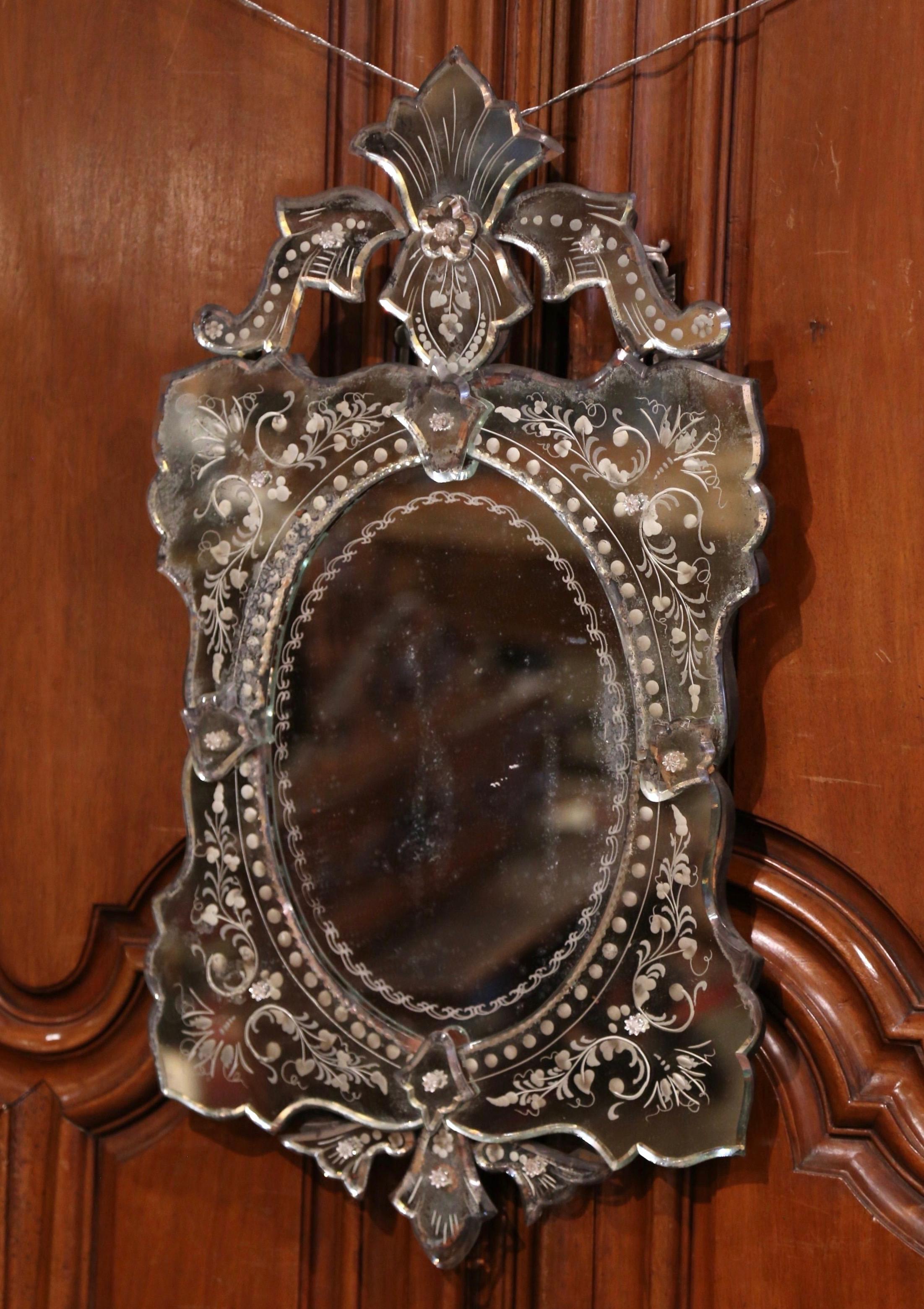 Decorate a powder room or a bedroom with this elegant, antique mirror; crafted in Venice, Italy, circa 1920, the wall mirror features a large carved leaf motif at the pediment, flanked by foliage on both sides. Each corner is decorated with hand