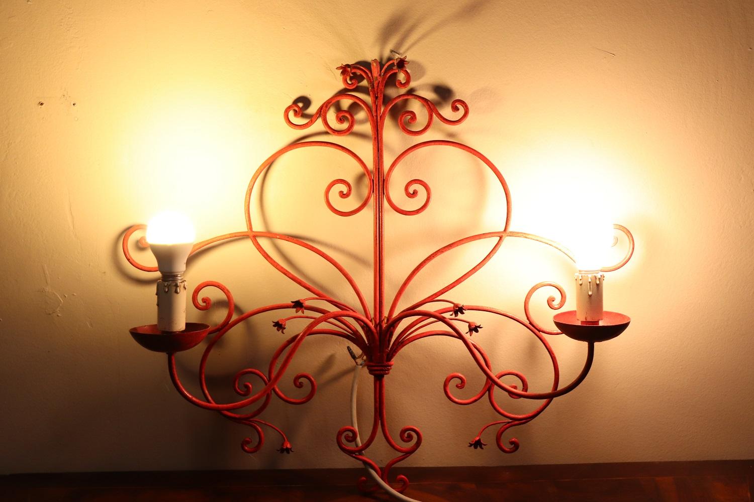 Beautiful and refined Italian early 20th century wall light or sconce with two lights. Made of red lacquered iron with elaborate decoration many spirals. Very decorative perfect for your wall. Signs of wear in the lacquer.
