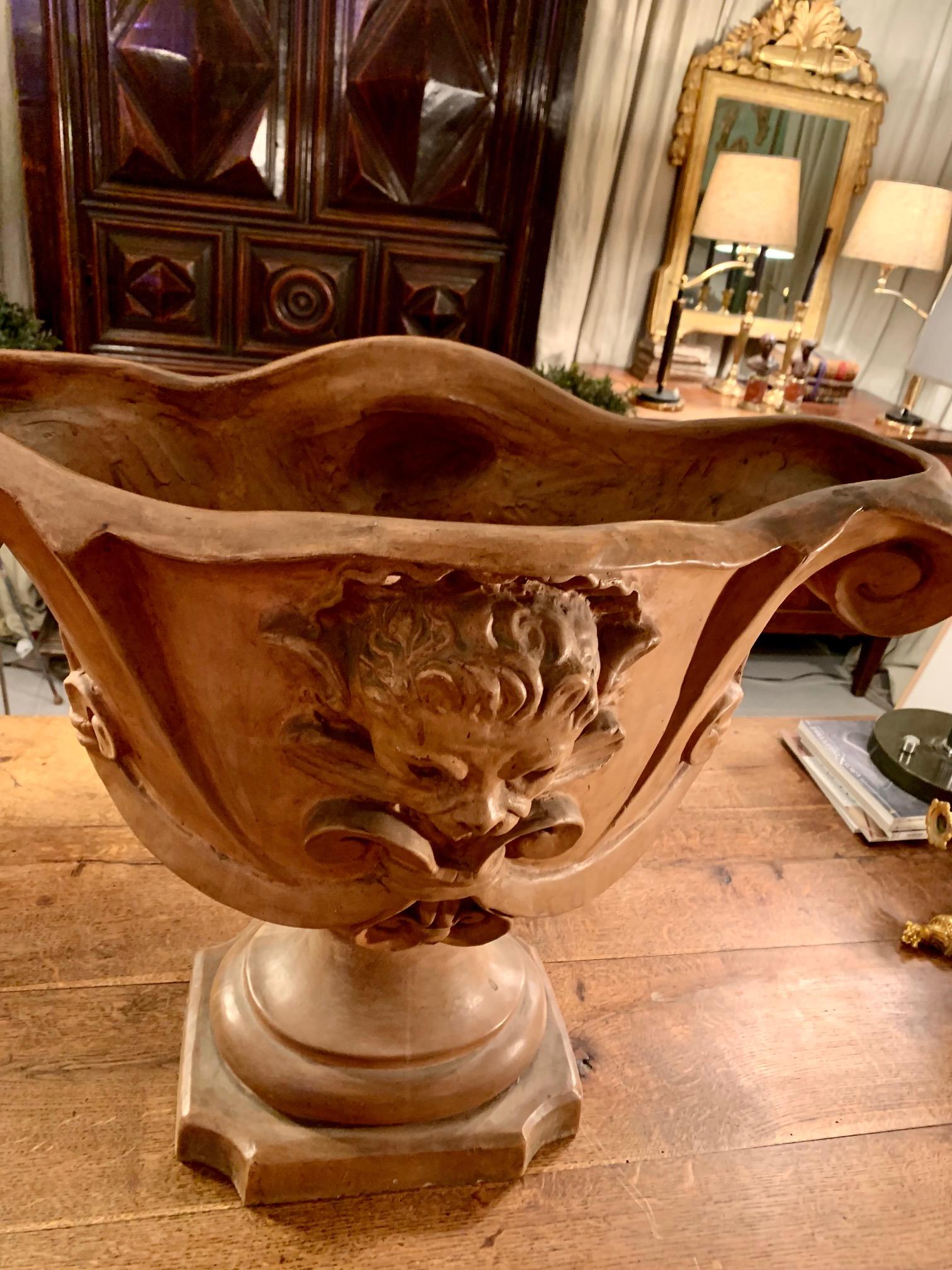 Eine große italienische Terrakotta-Urne oder Vase mit geformtem Schneckendekor und einem Löwenkopf auf der Vorderseite ist ein sehr dekoratives Objekt.