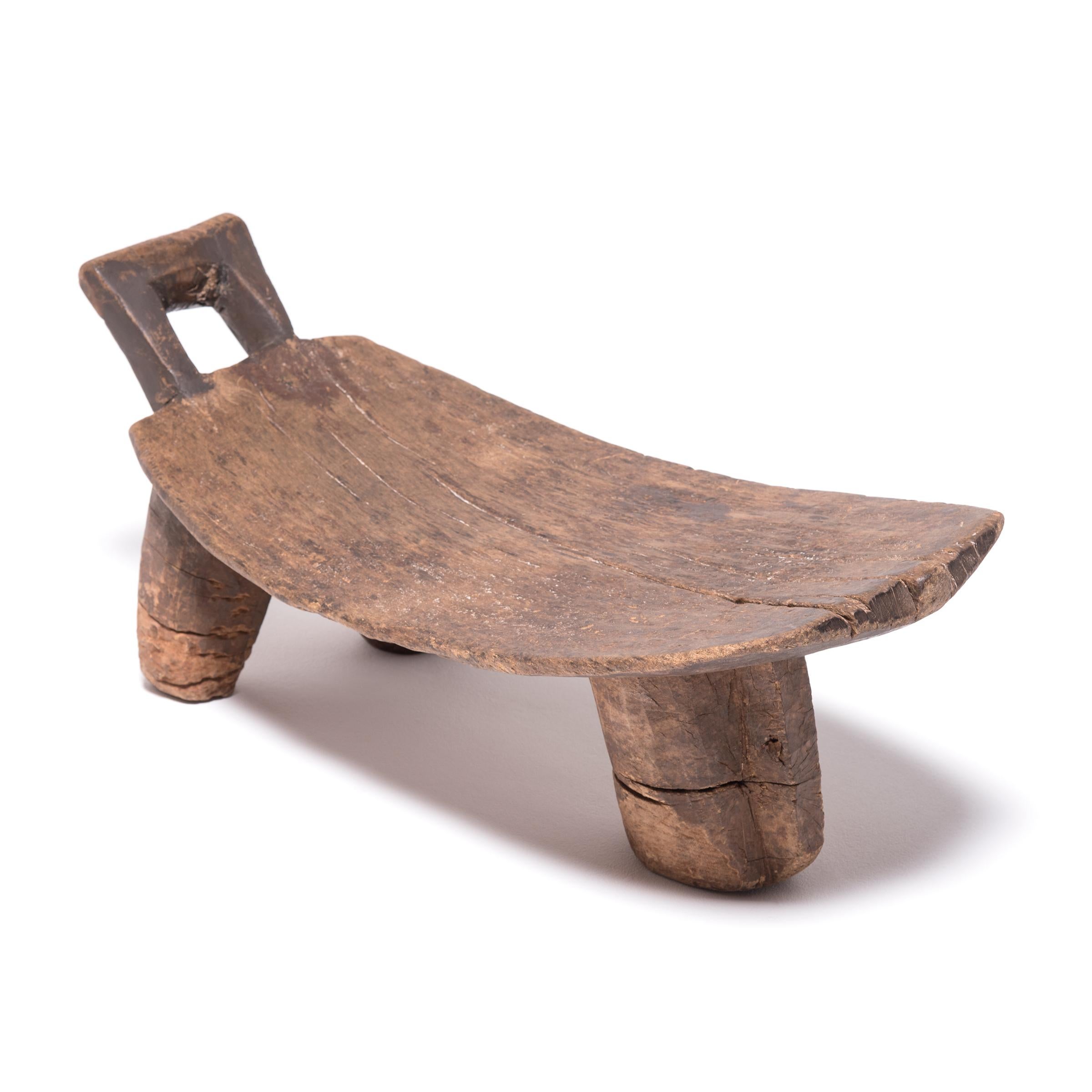 The combination of stout legs and a gracefully curved seat mark this baby bed as an exciting example of Senufo craftsmanship. In contrast to many of their stools, this baby bed features a longer seat that transitions into a simply carved headrest.