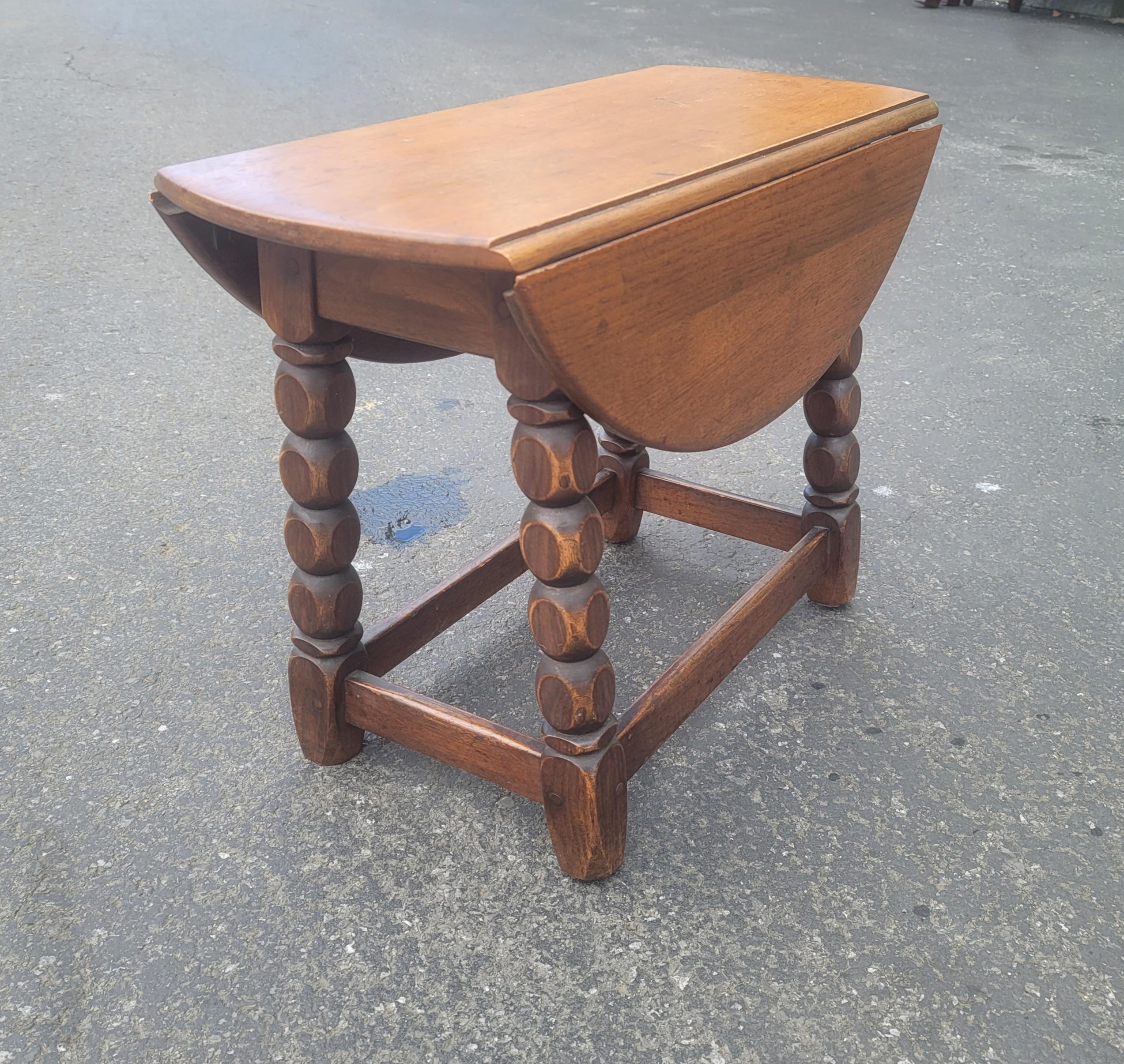 An early 20th century Jacobean low oak drop-leaf side table. Measuring 25 inches in diameter with leaves up. Table is 11.5