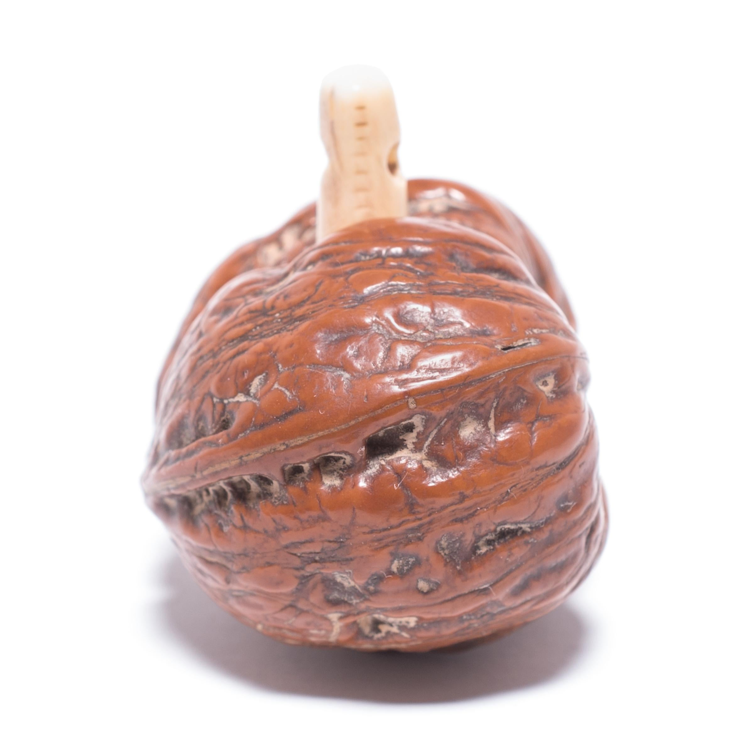Japanese artisans have long held mastery in the creation of miniature treasures, or netsuke. This gourd is ingeniously carved out of a walnut shell with a polished bone spur acting as the stem at the gourd's top. A symbol of divinity, good fortune