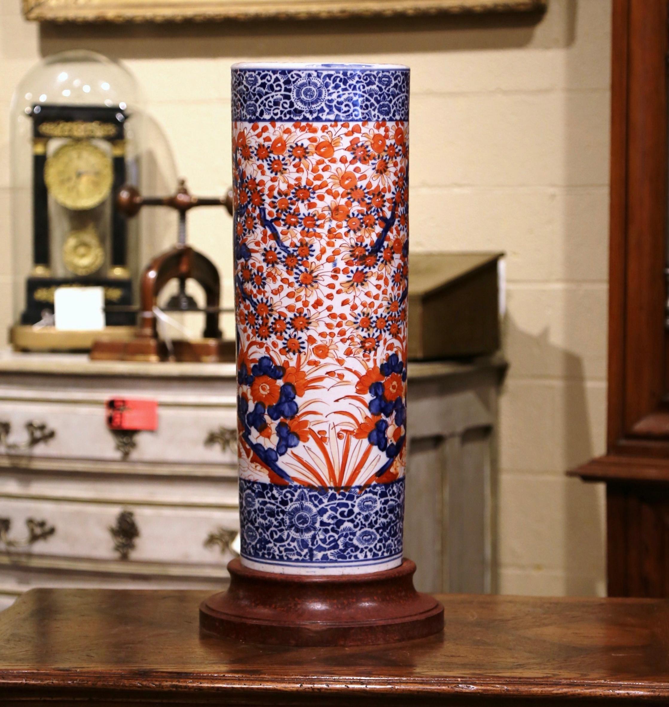Place this elegant antique stand at your front door or in your mudroom to catch loose canes and umbrellas. Crafted in Japan circa 1920 and round in shape, the porcelain piece sits on a carved wooden base, and features colorful hand painted floral