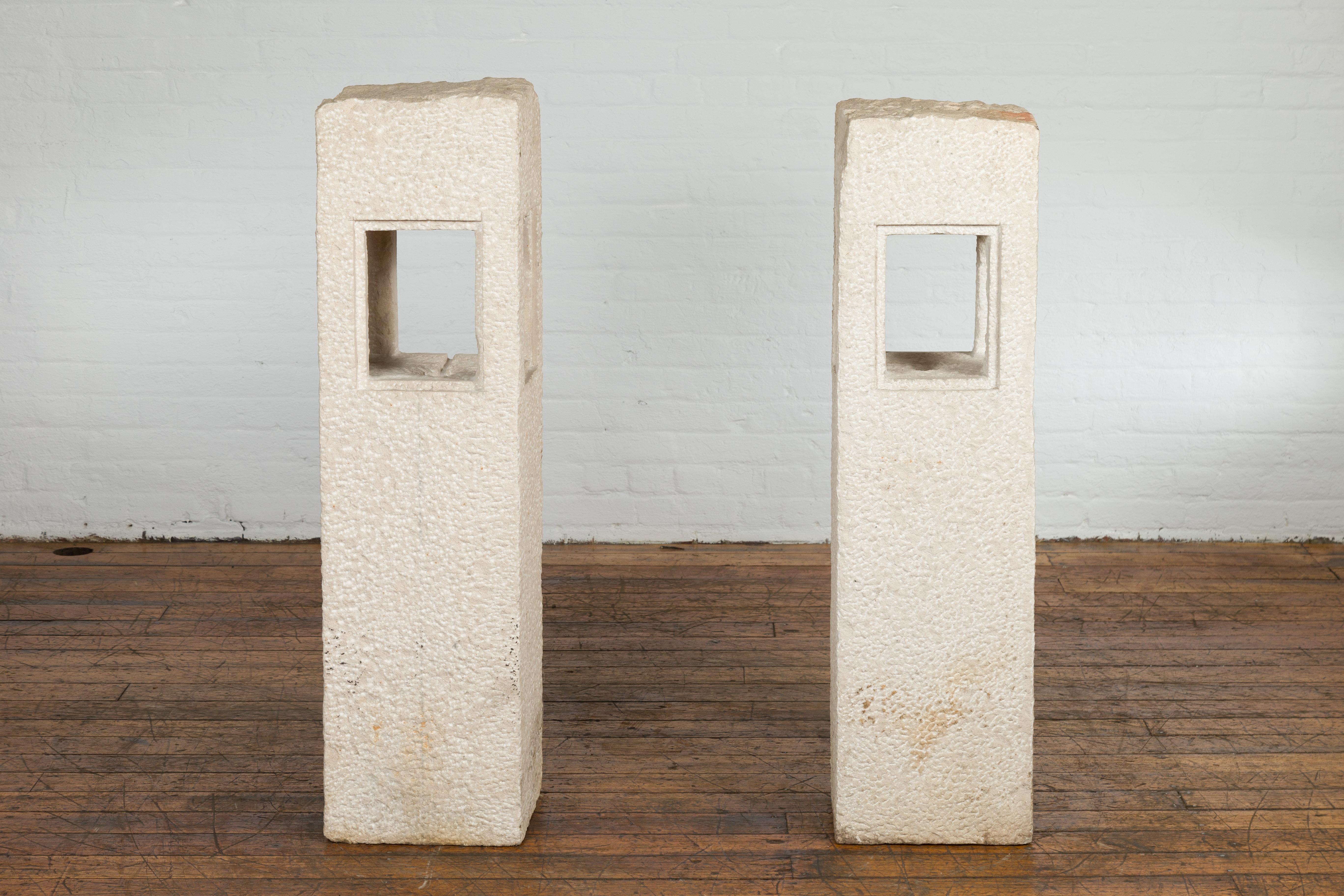 A pair of Japanese Toro stone lanterns from the early 20th century, with candle holders and wax area. Created in Japan during the early years of the 20th century, this pair of Toro stone lanterns features a linear silhouette accented by a central