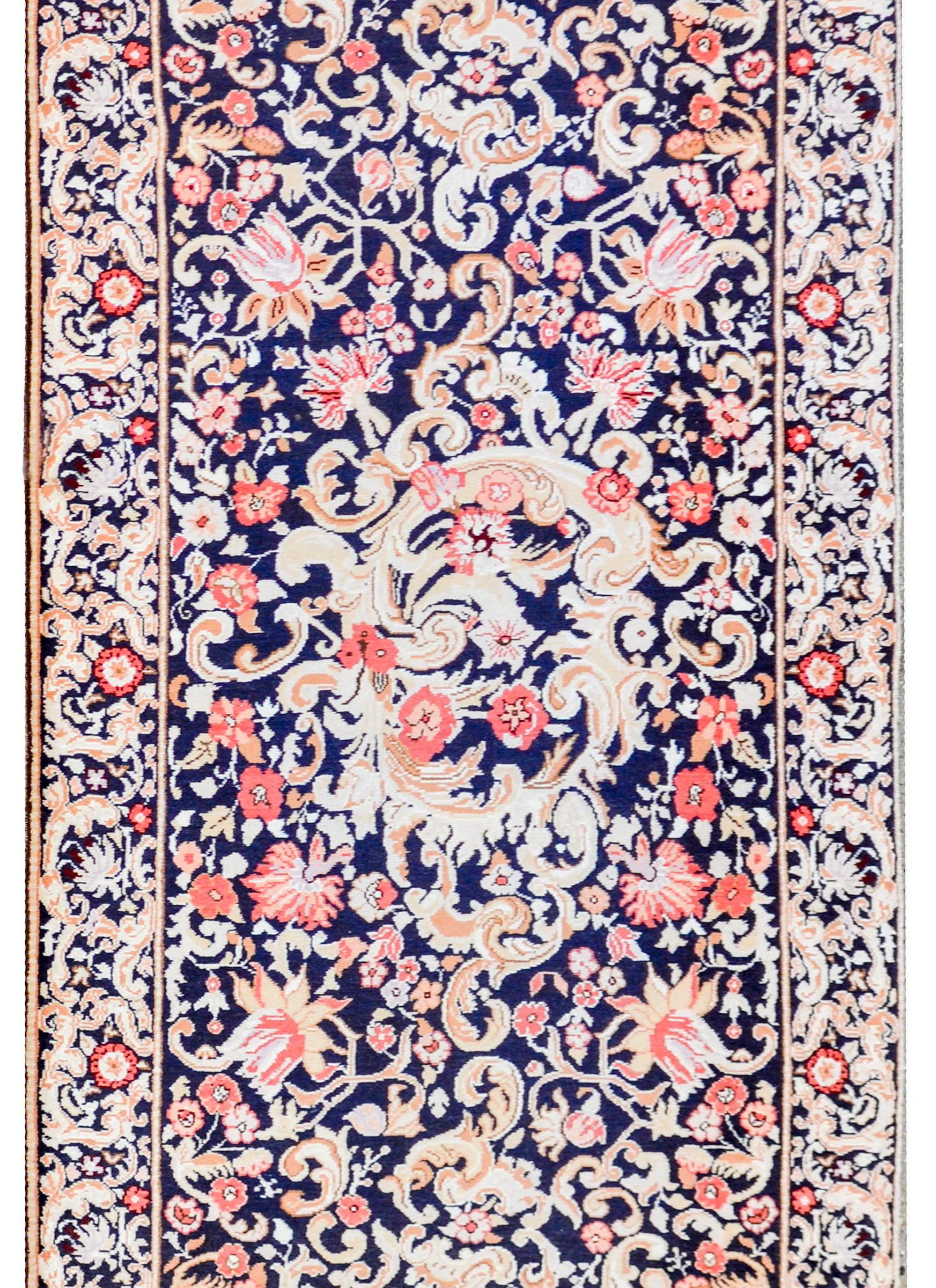 Early 20th century Persian Kareback rug with a densely woven baroque pattern of scrolling acanthus leaves and myriad flowers woven in varying shades of brown and gold, pink and crimson, on a black background. The border is similarly patterned, but
