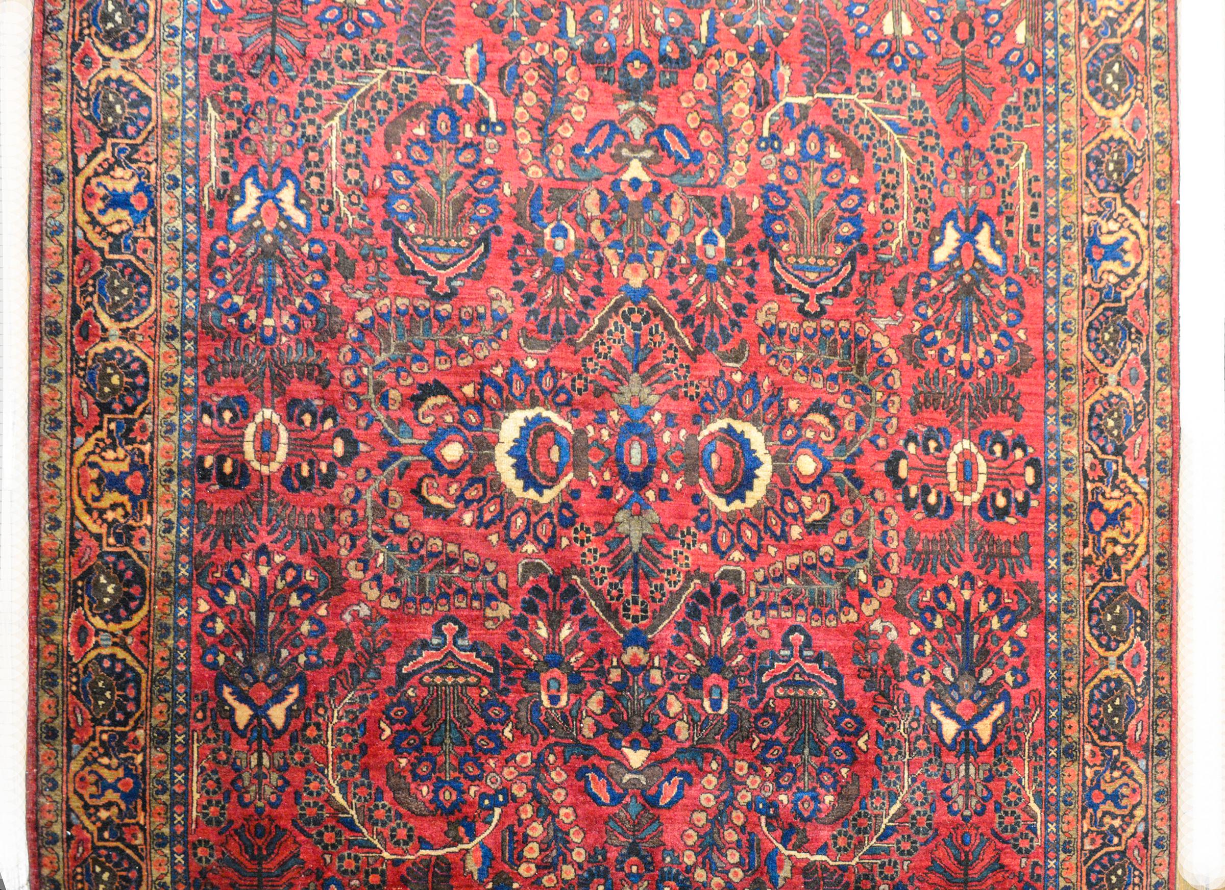 Un meraviglioso tappeto persiano Kashan dell'inizio del XX secolo con un grande motivo floreale specchiato all-over tessuto in lana indaco, crema, rosa e marrone su uno sfondo cremisi. Il bordo è ampio con una striscia larga a motivi floreali