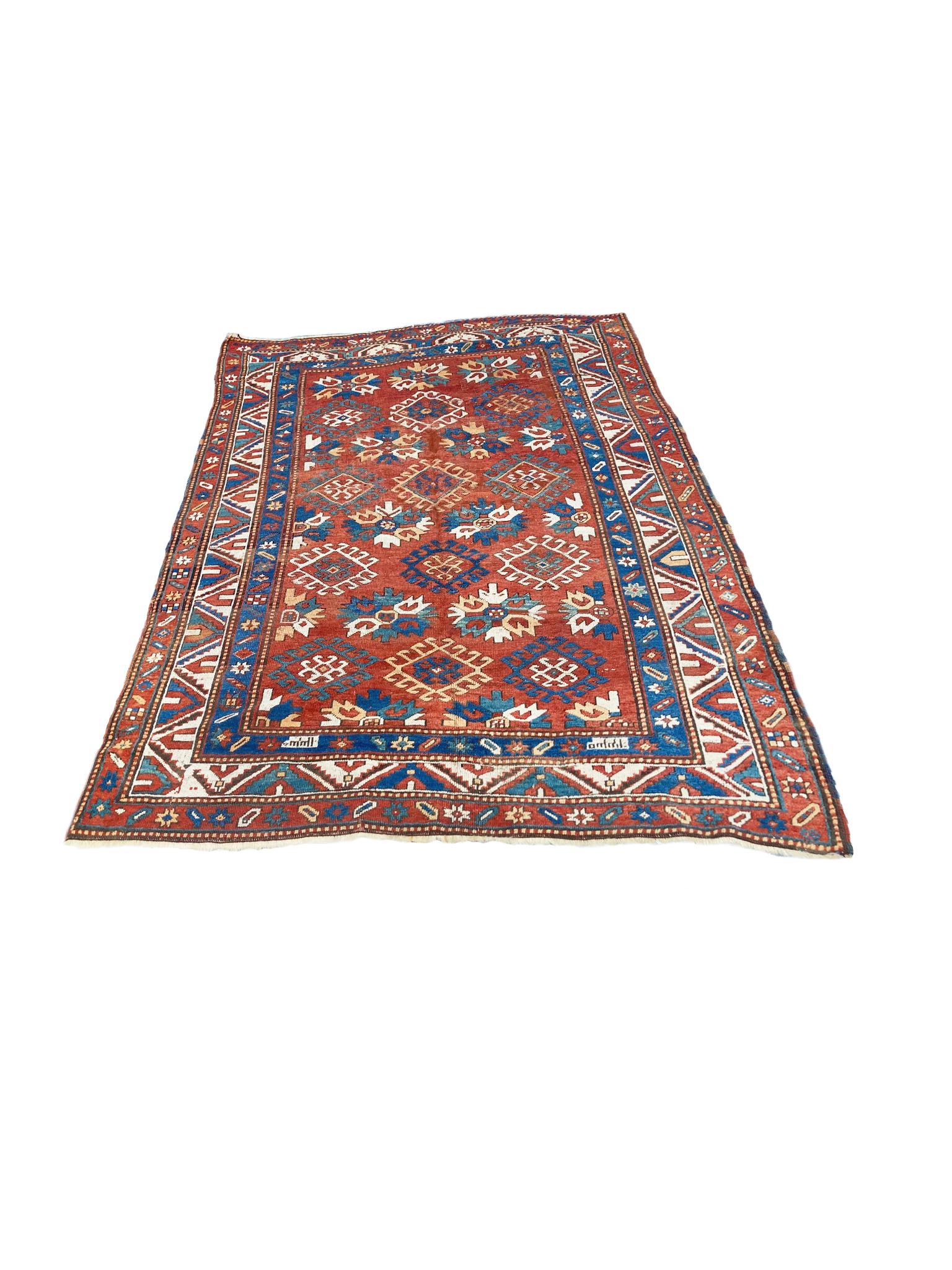 Kazak rug woven in the Early 20th Century. Rich palette of reds, yellows, blues, and ivory. The design is features a center red field with rows of medallions and floral motifs, framed by a series of borders with geometric patterns in the same