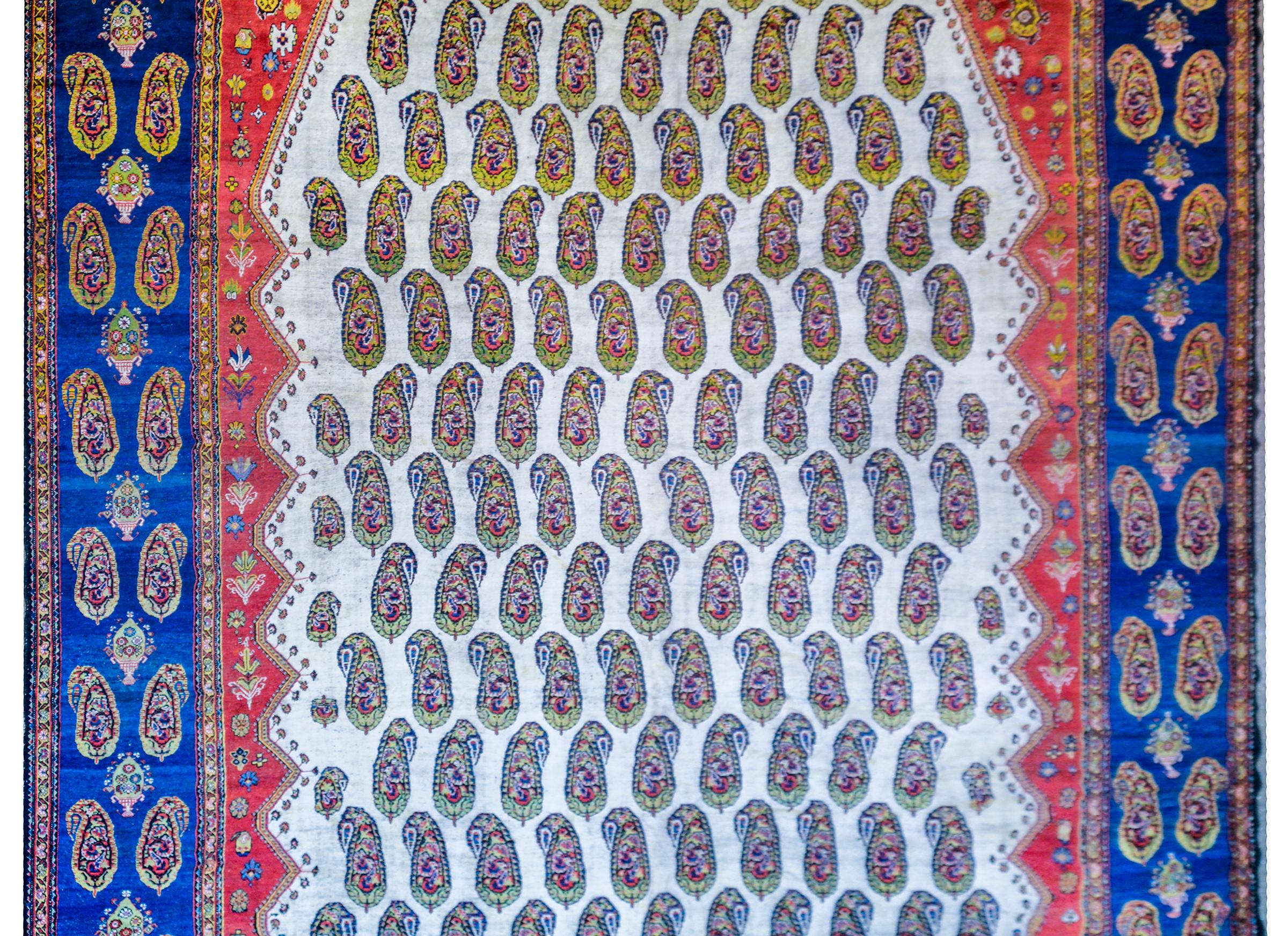 An incredible early 20th century Persian Khamseh rug with an all-over multicolored paisley pattern on a white background surrounded by a complimentary border of multicolored paisleys on an indigo background.
