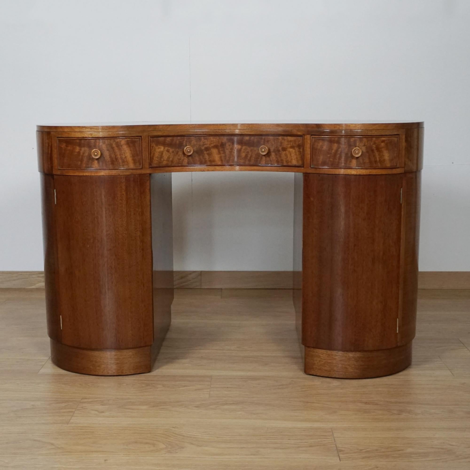 An Early 20th Century kidney shaped desk. Flame mahogany veneered on solid mahogany. Three upper drawers with two lower cupboard sections alos with interior drawers. 

Dimensions: H 77cm W 122cm D 60cm Aperture H 63cm W 45cm 

Origin: English

Date: