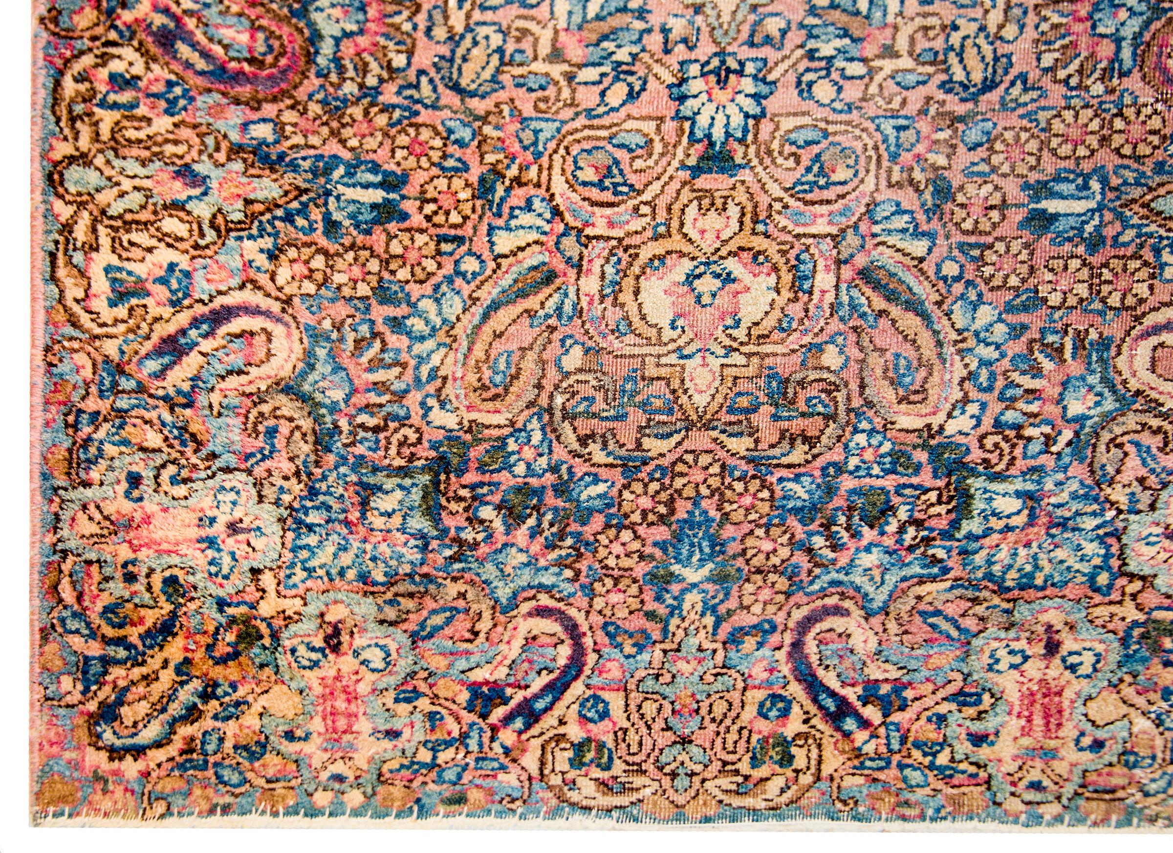 An early 20th century Persian Kirman rug with a beautiful all-over floral and paisley pattern woven in traditional Kirman colors of cranberry, light and dark indigo, and cream vegetable dyed wool. The border blends in with the field to create an