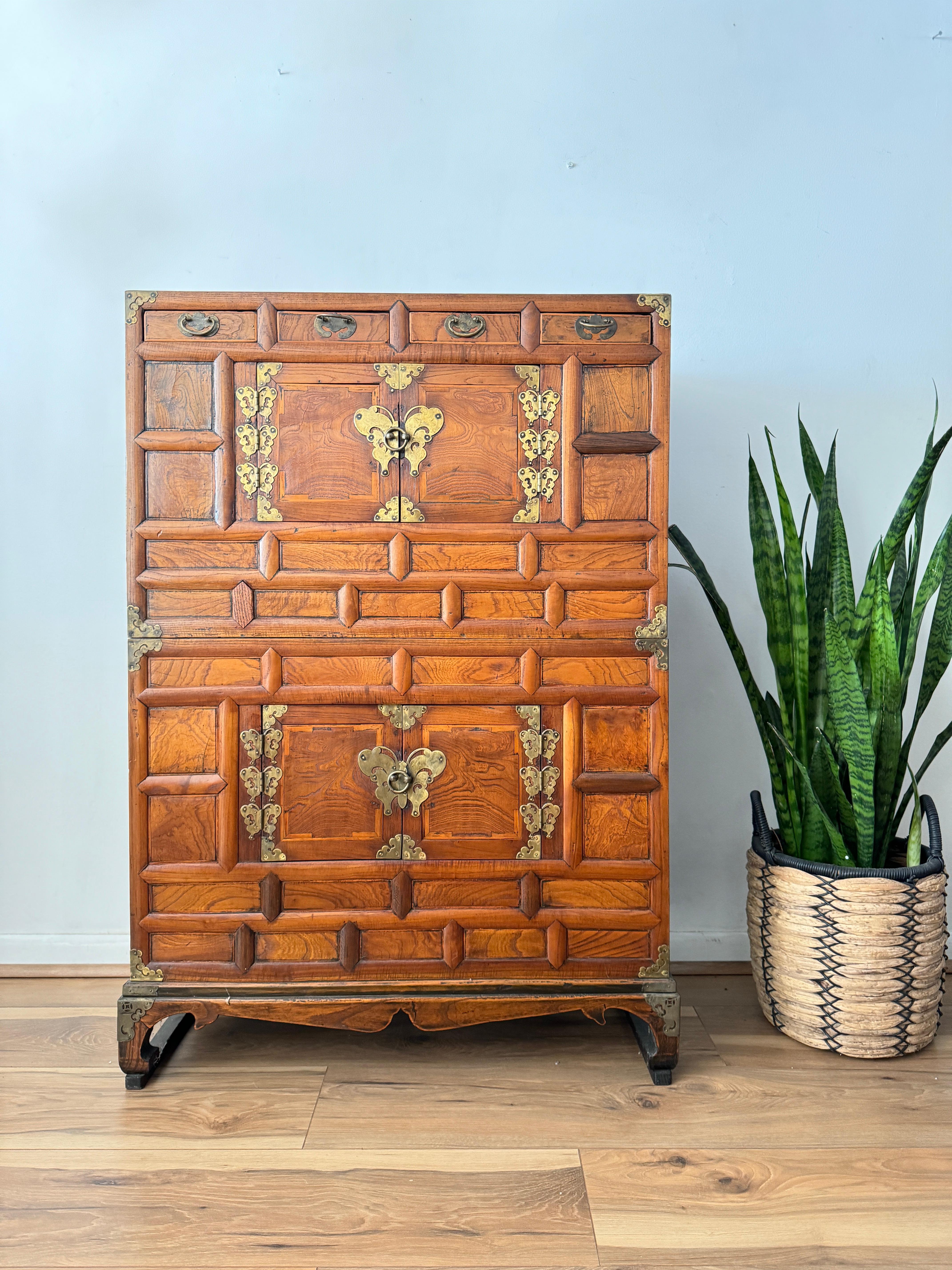 This is an exquisite two-part Korean Tansu cabinet from the early 20th century. The upper case features four small fitted drawers, while both upper and lower cases have central doors leading to storage compartments adorned with paper featuring
