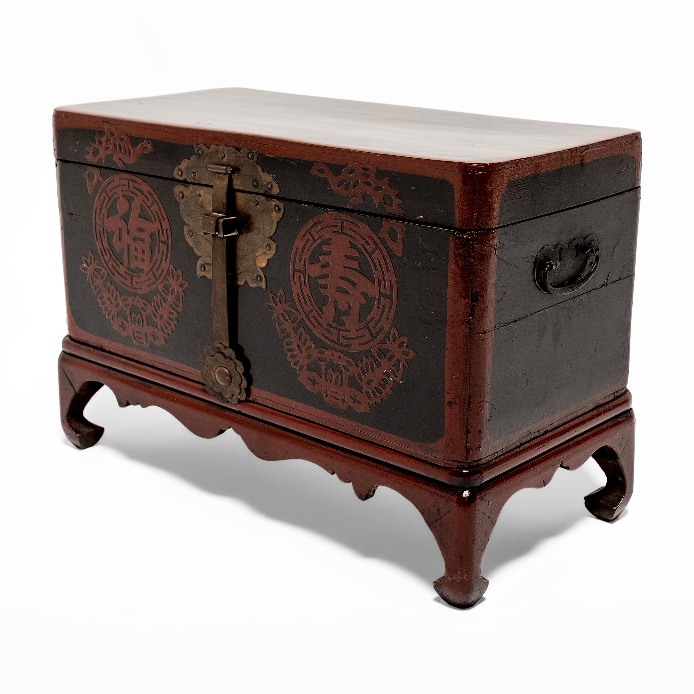 This lacquered wedding chest dates to the early 20th century and was likely originally used as a bridewealth chest during a traditional Korean wedding ceremony. The exterior is finished with red and black lacquer and decorated with two round