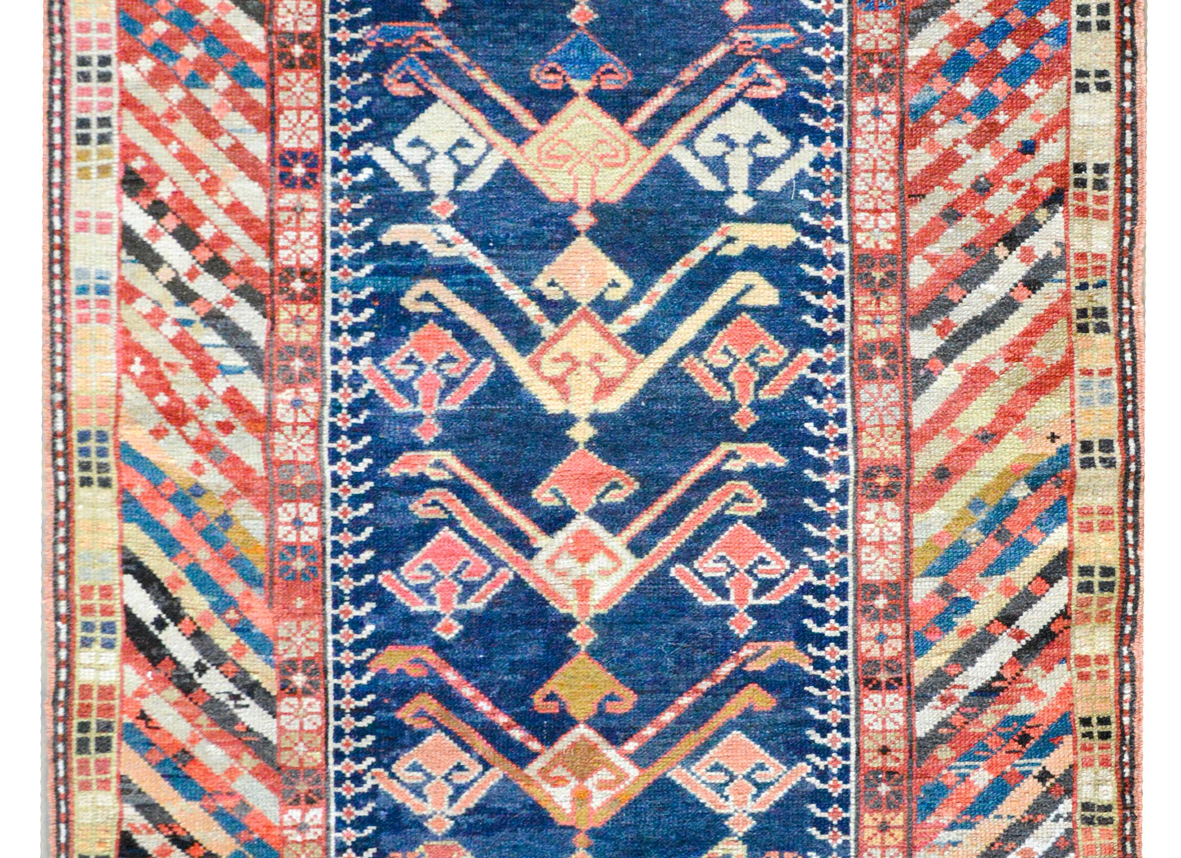 An outstanding early 21st century Kuba-style rug with a bold stylized floral pattern set against an indigo background, and surrounded by an unusual multi-colored striped border flanked by two geometric and stylized floral patterned stripes.